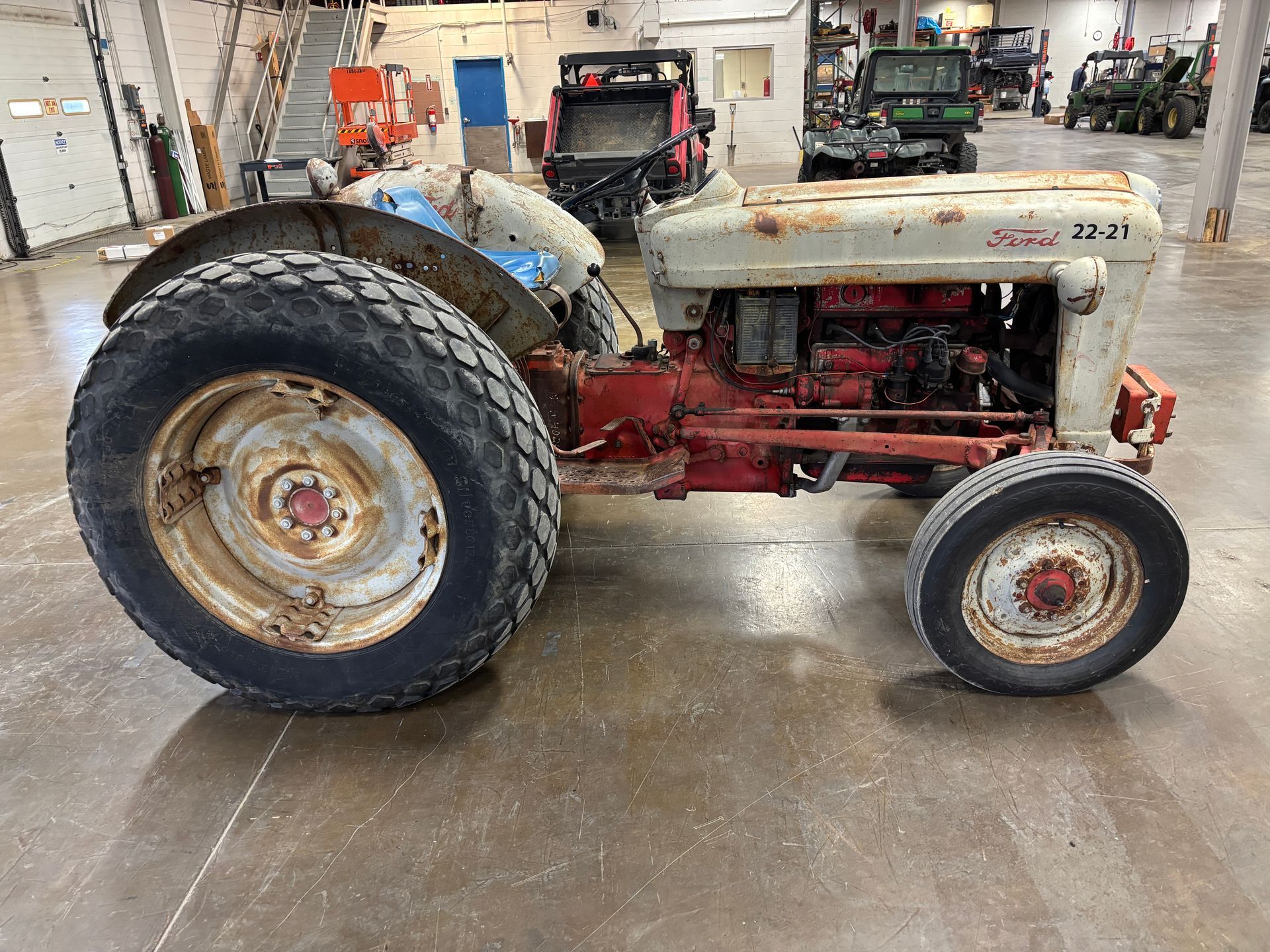 Rusty Ford 2N tractor with white and red paint, in a workshop.