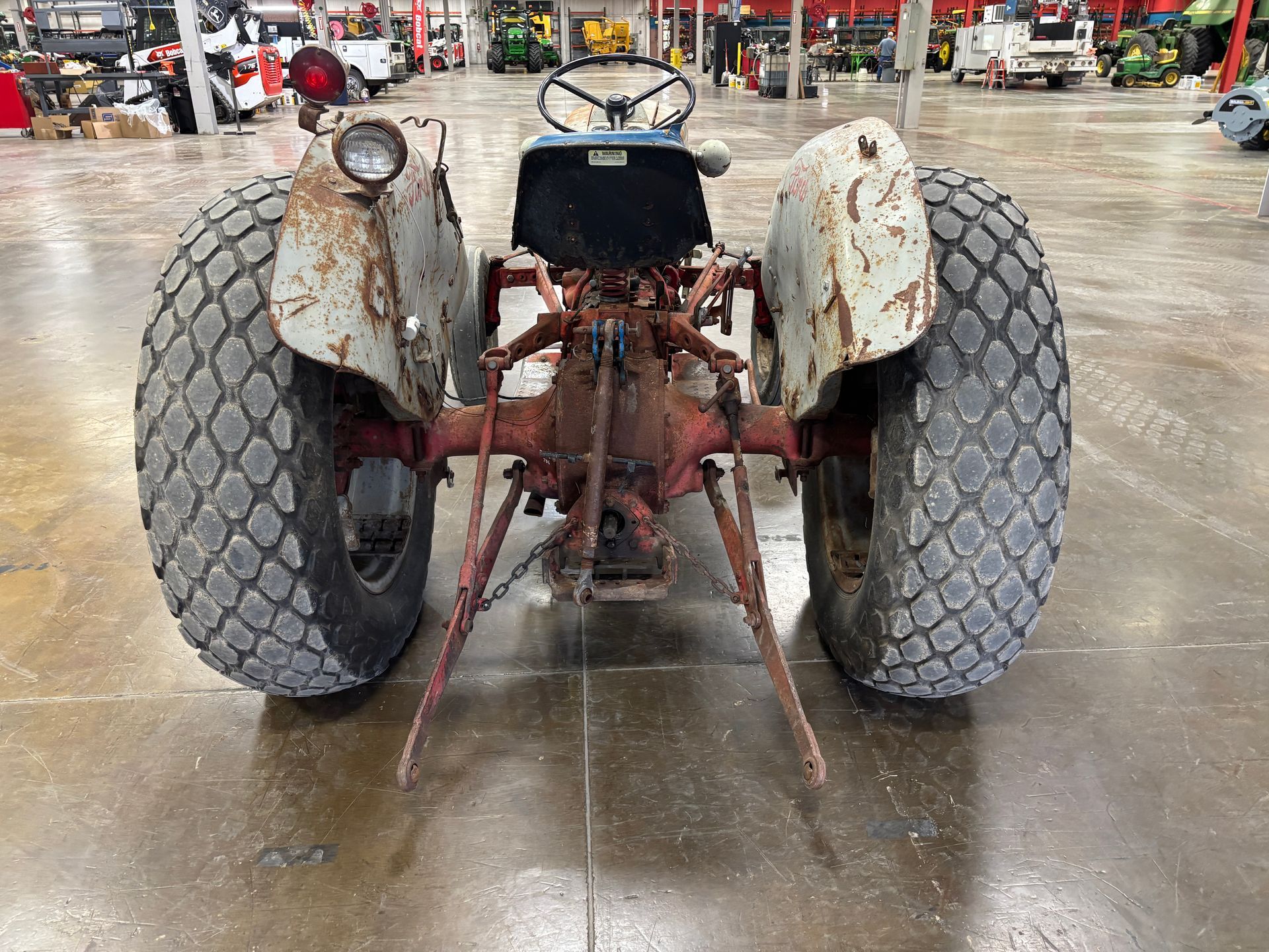 Rear view of a rusty blue and red farm tractor with large tires.