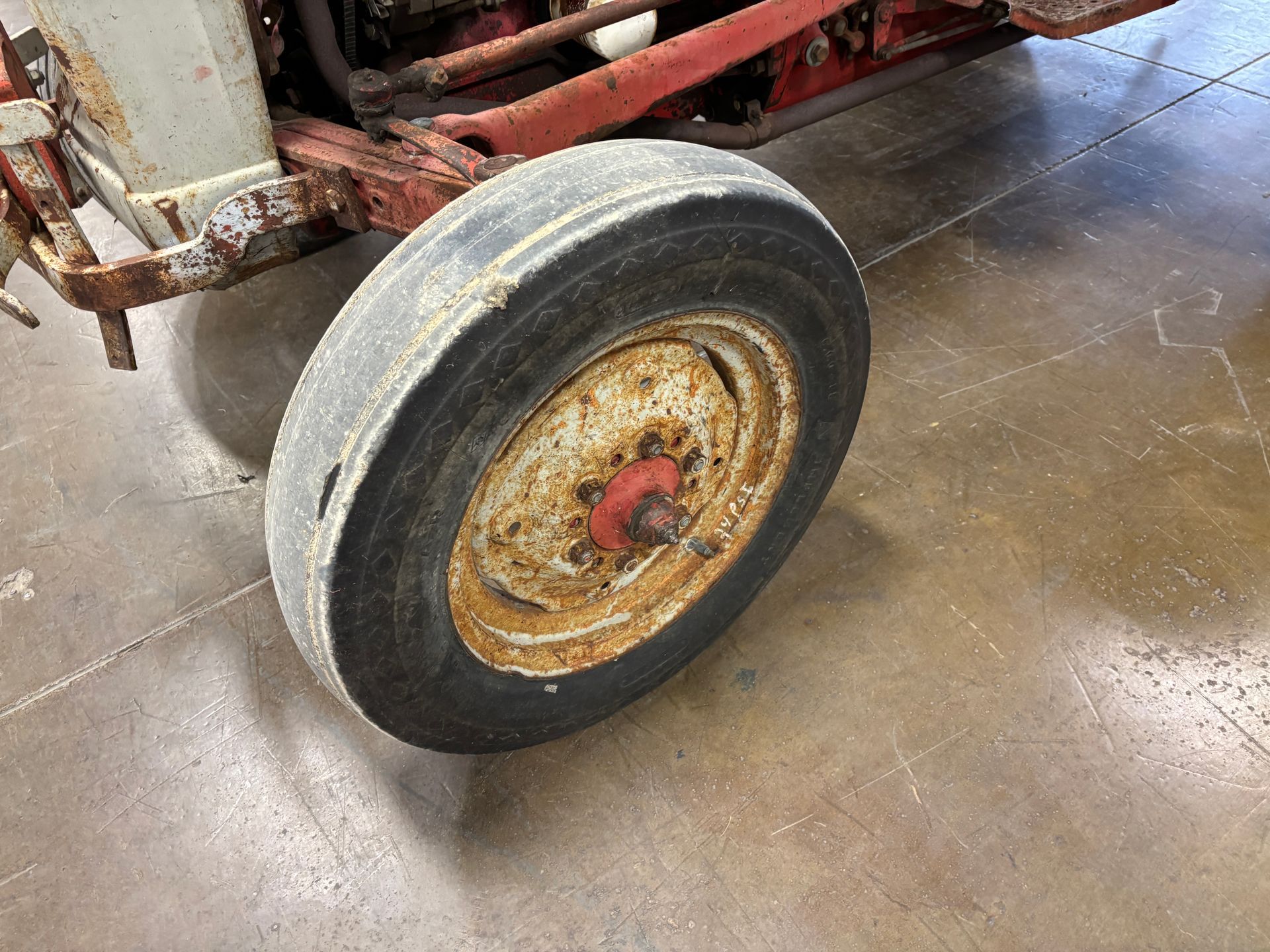 Rusty Ford 8N tractor with red and white paint, parked inside a warehouse.