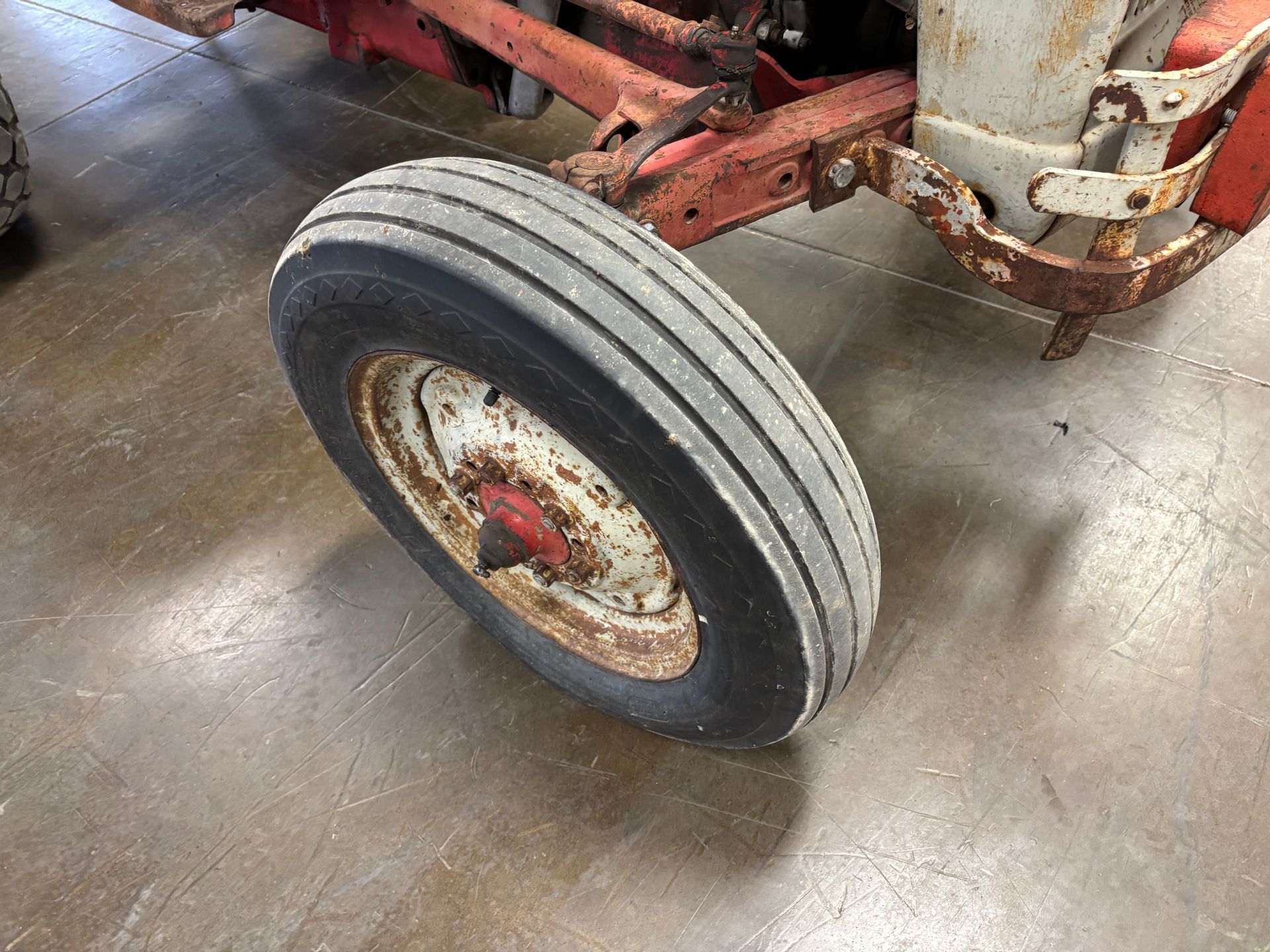 Rusty tractor wheel on a metal surface, with visible tire tread and red hub.