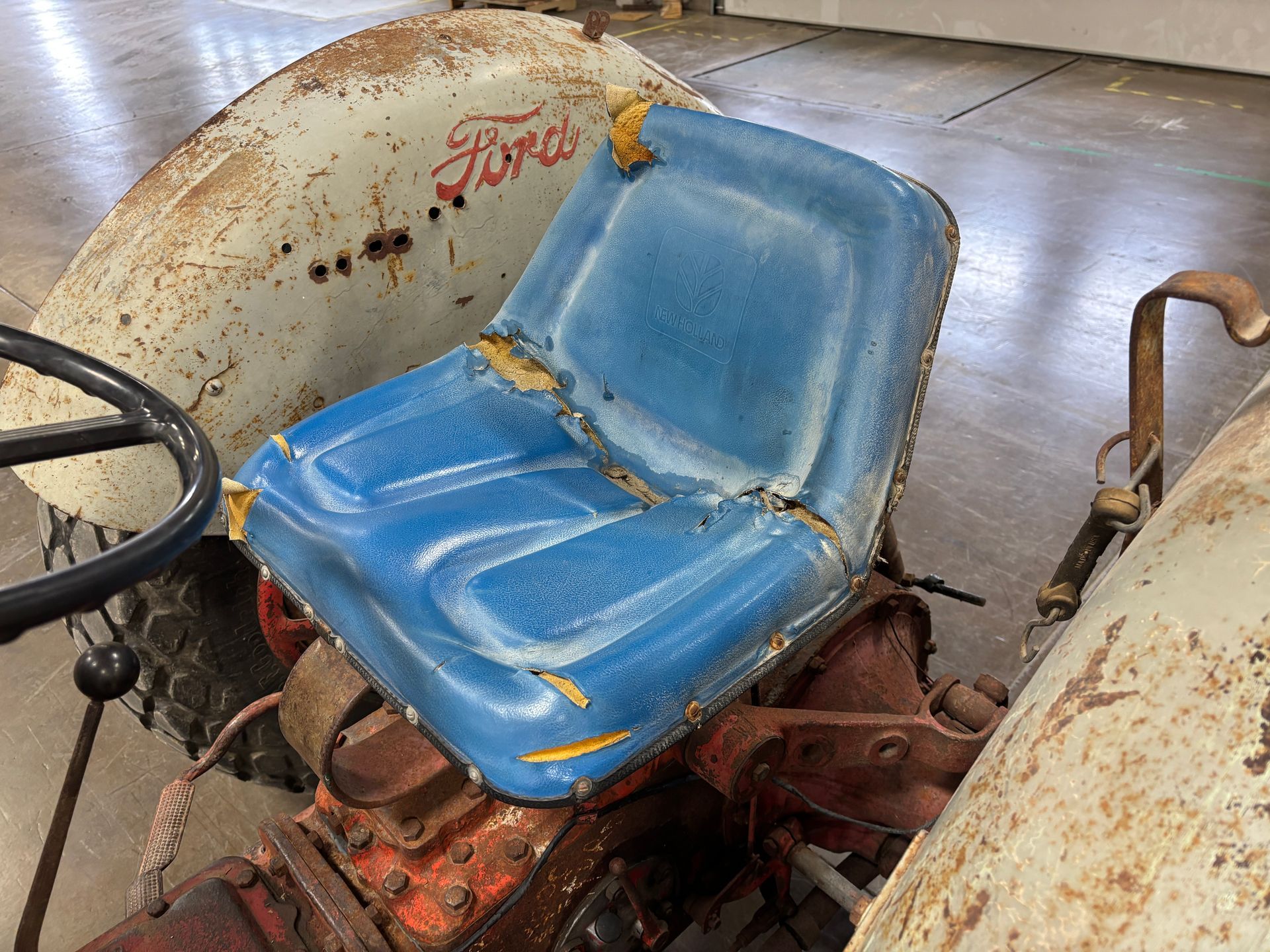 Old Ford tractor with blue, worn seat and weathered body.