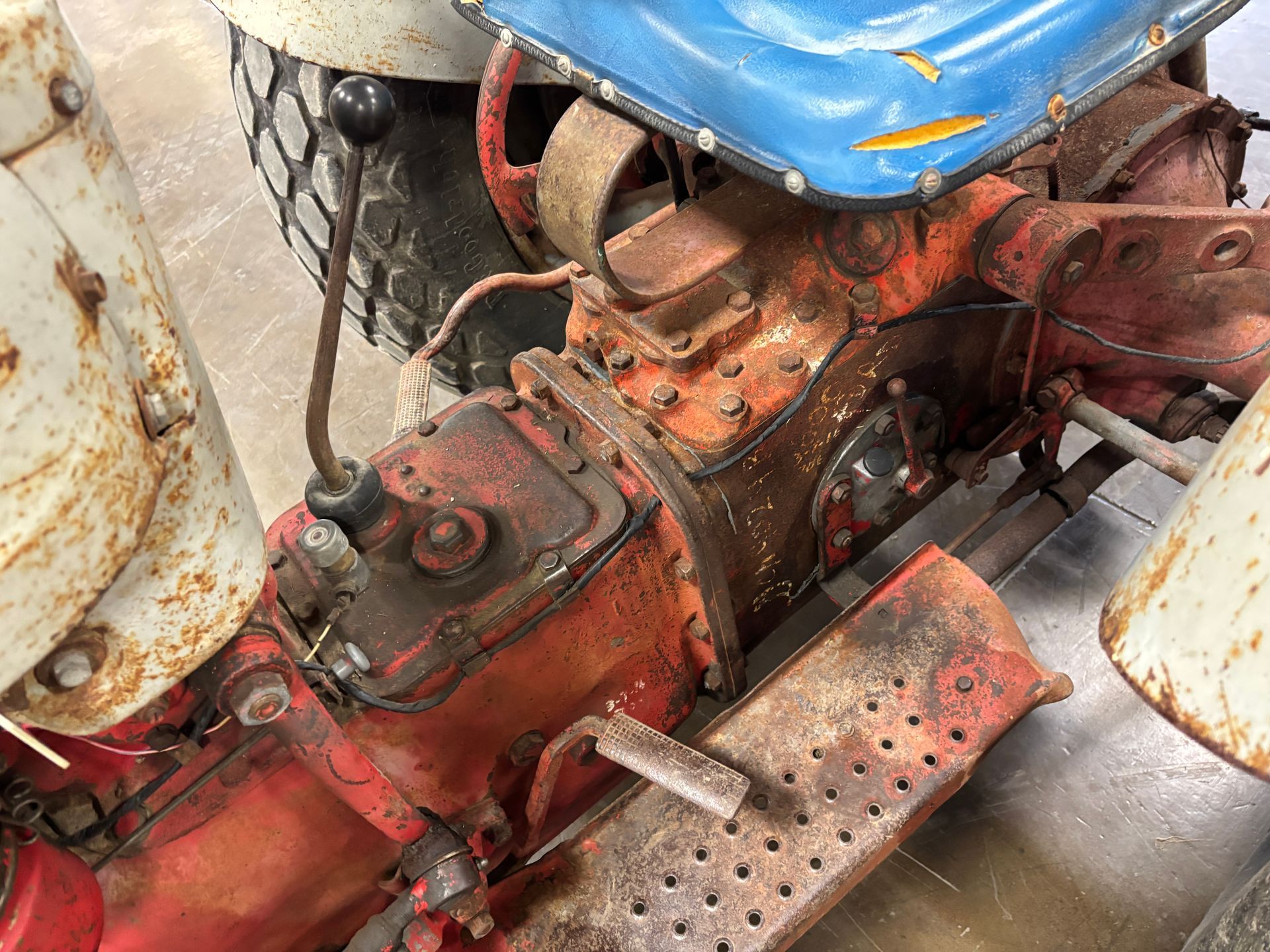 Overhead view of an aged, orange and white tractor's engine and seat, showing wear and tear.