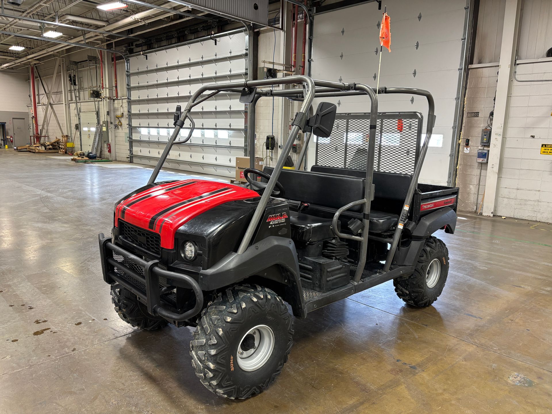 Black and red utility vehicle with roll cage, parked in an industrial building.