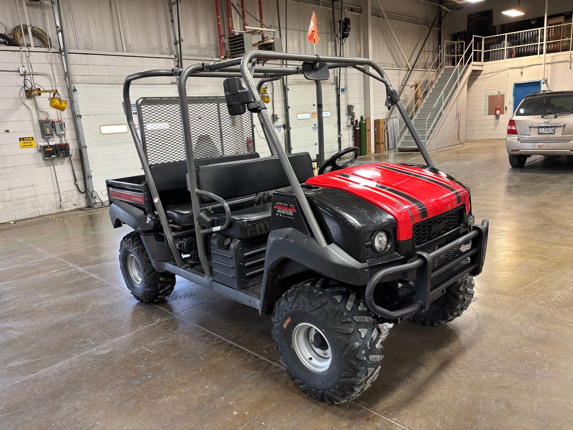 Black and red ATV-like vehicle with roll cage, in a garage.