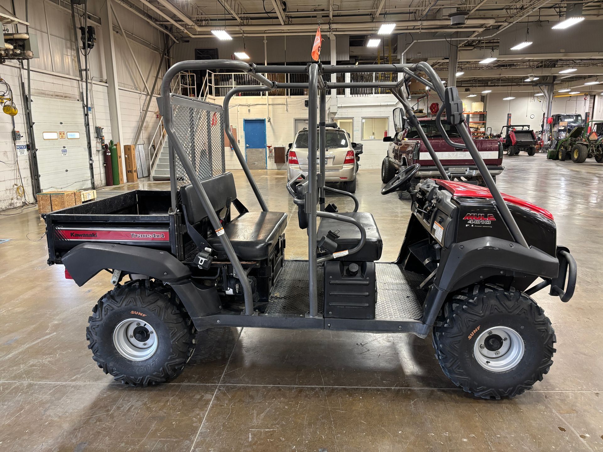 Black and red ATV-style utility vehicle with roll cage parked inside a warehouse.