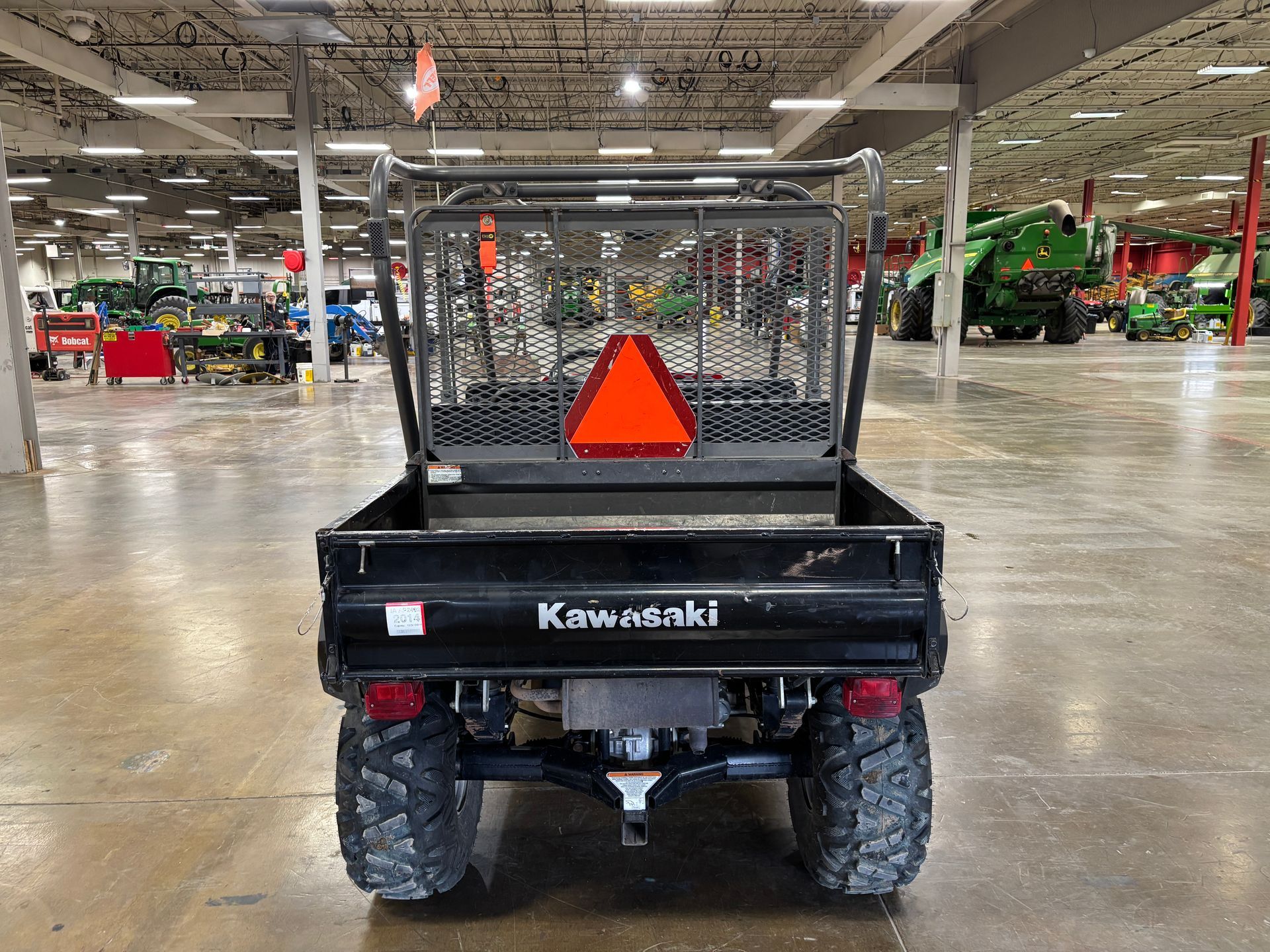 Black Kawasaki utility vehicle with a bed, showing a red triangle, and large tires.