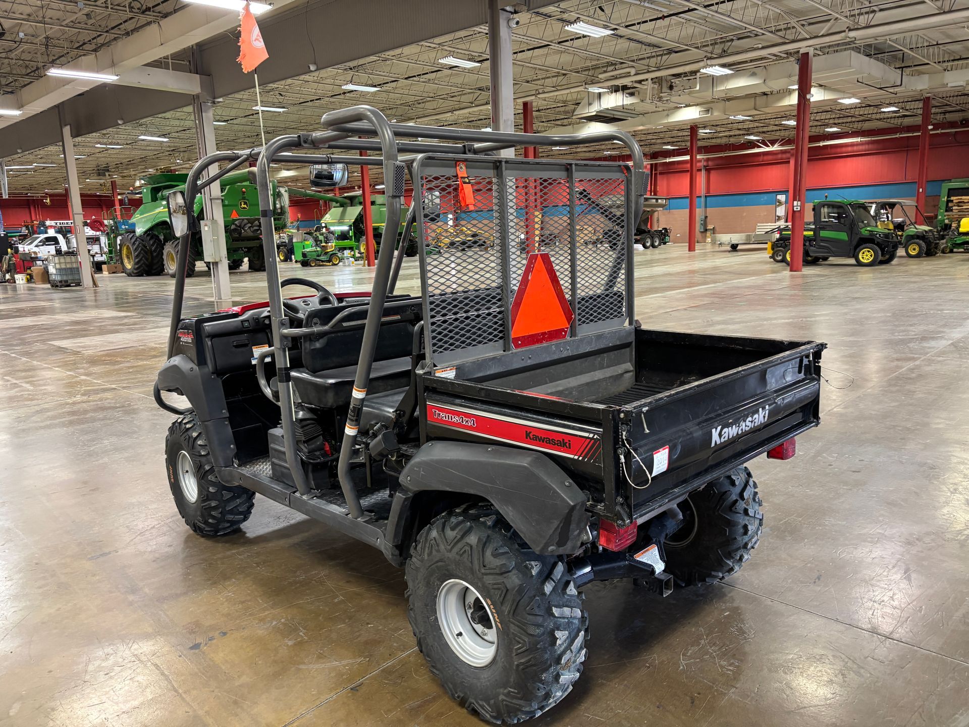 Kawasaki Mule utility vehicle in a large warehouse with agricultural equipment.