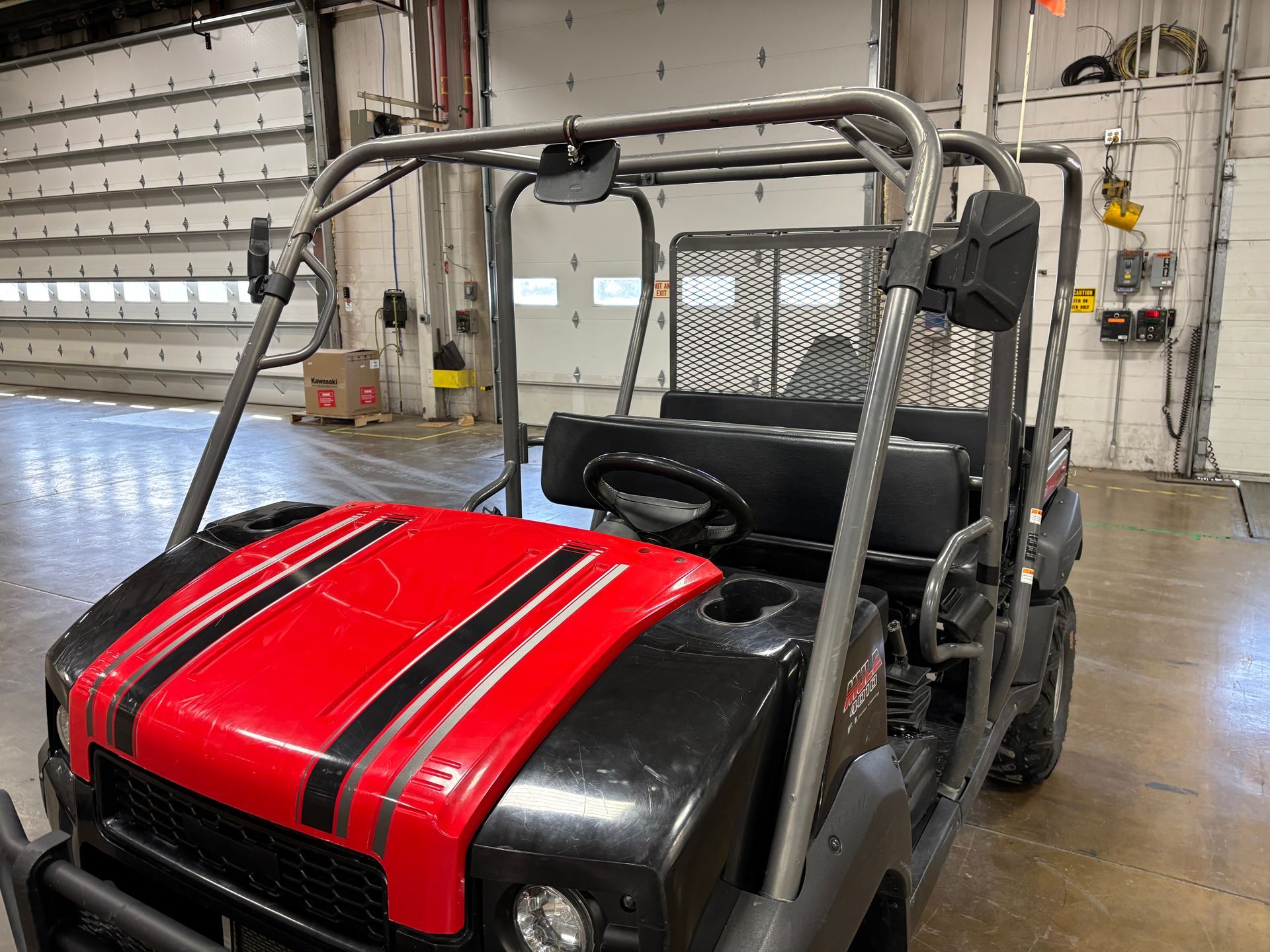 Red and black utility vehicle with roll cage parked inside a warehouse.