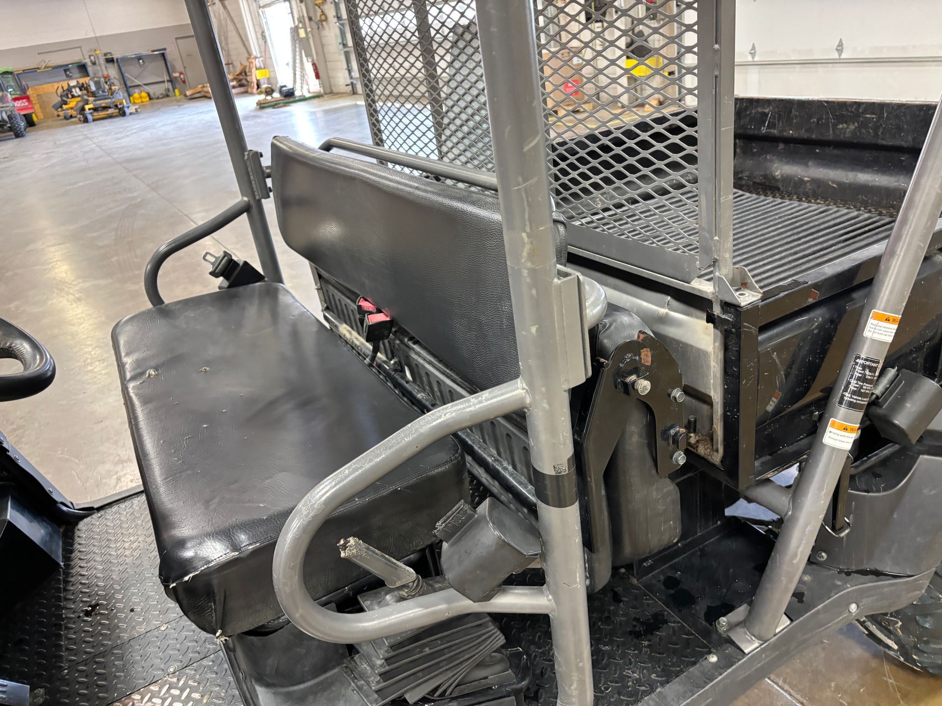Black utility vehicle seat and cargo area. Grey metal roll bars and safety cage.