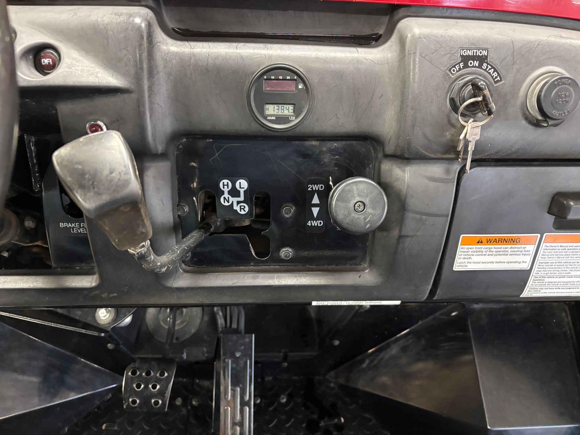 Dashboard with gear selector, speedometer, key, and other controls in a red vehicle.