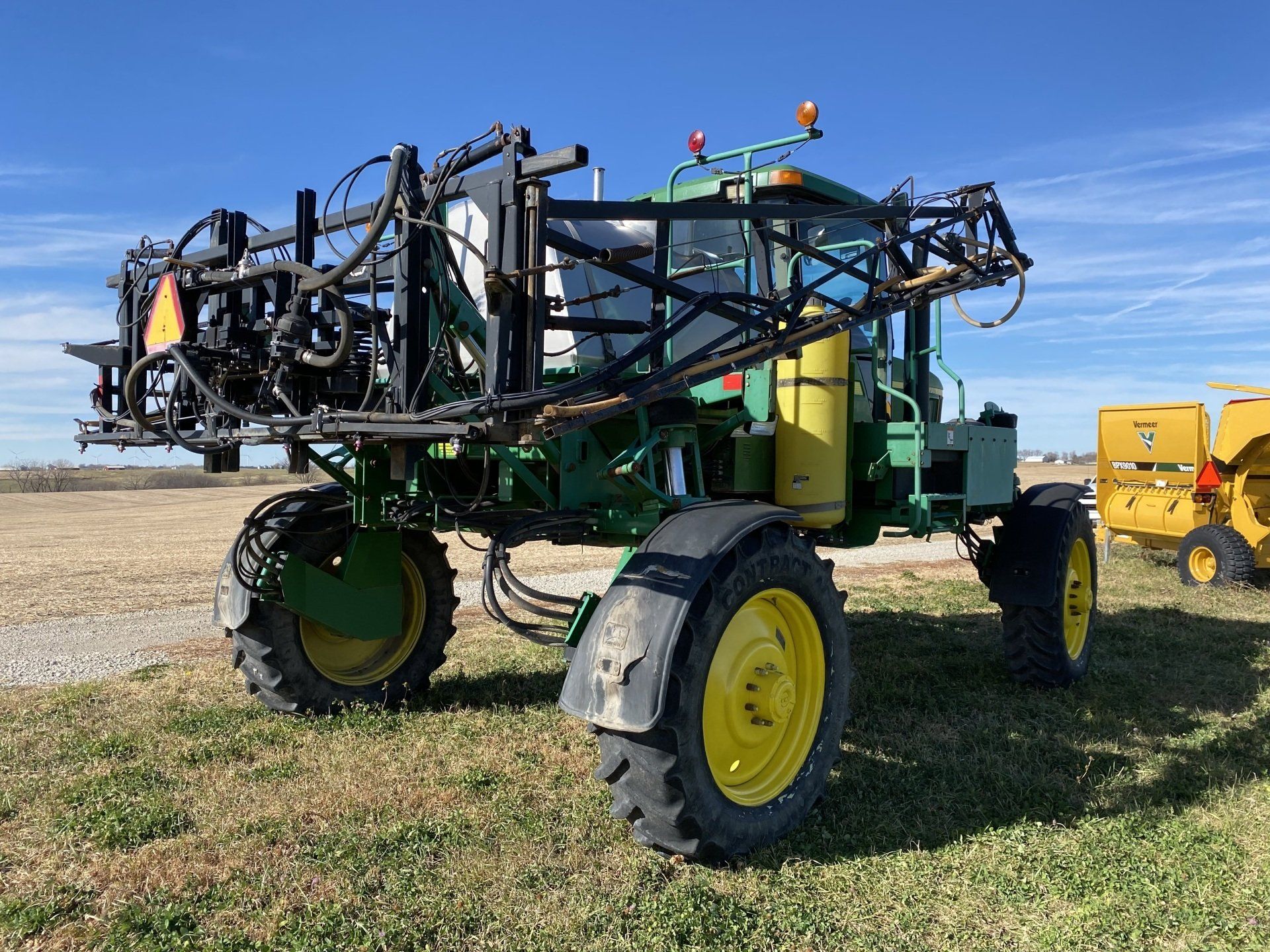 Green and yellow John Deere agricultural sprayer on a grassy field.