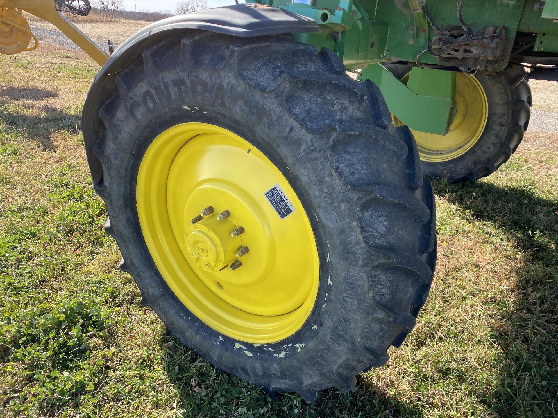 Yellow tractor wheel with black tire on green grass.