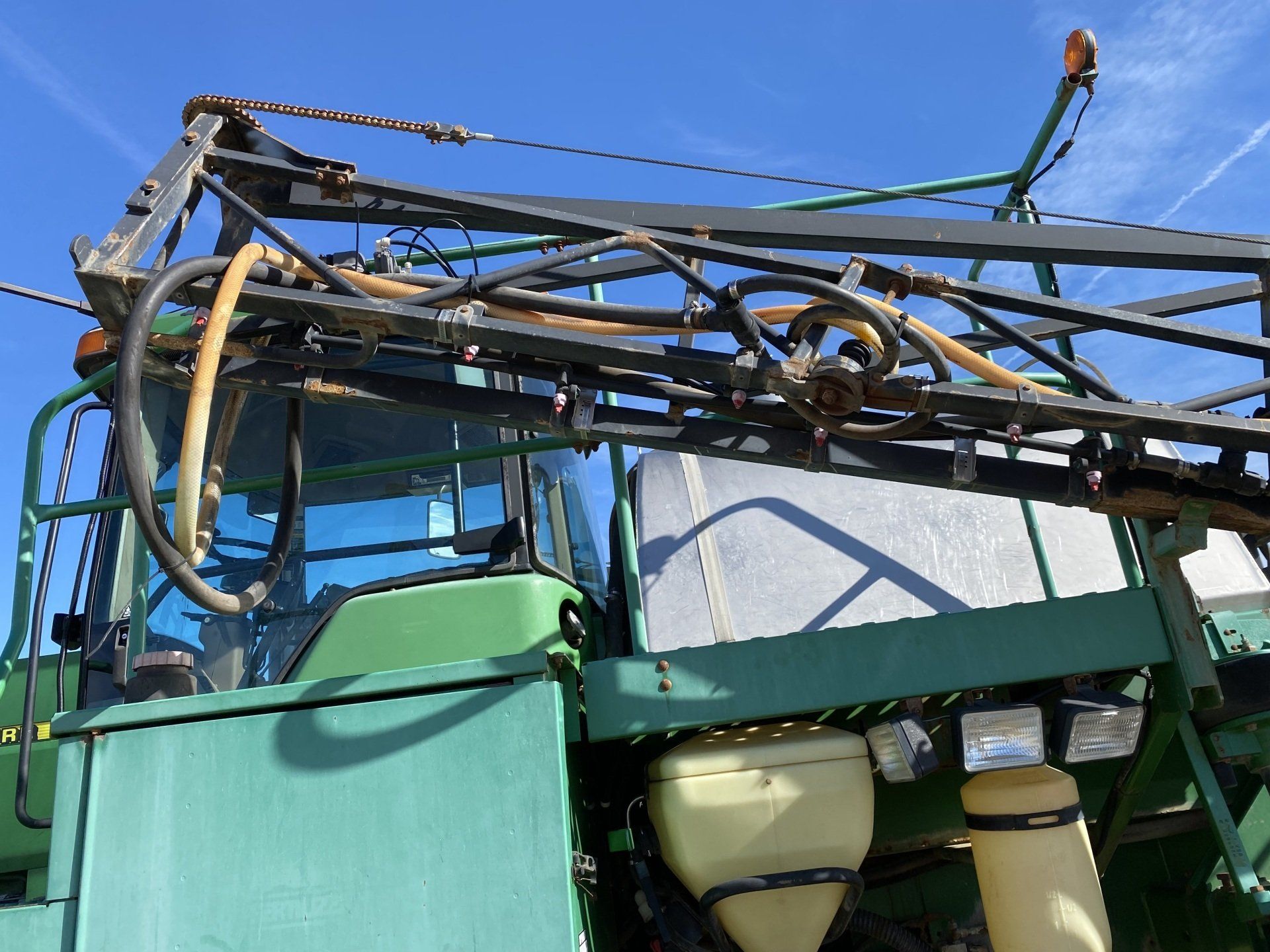 Green John Deere agricultural machine, with tire, steps, and control panel.
