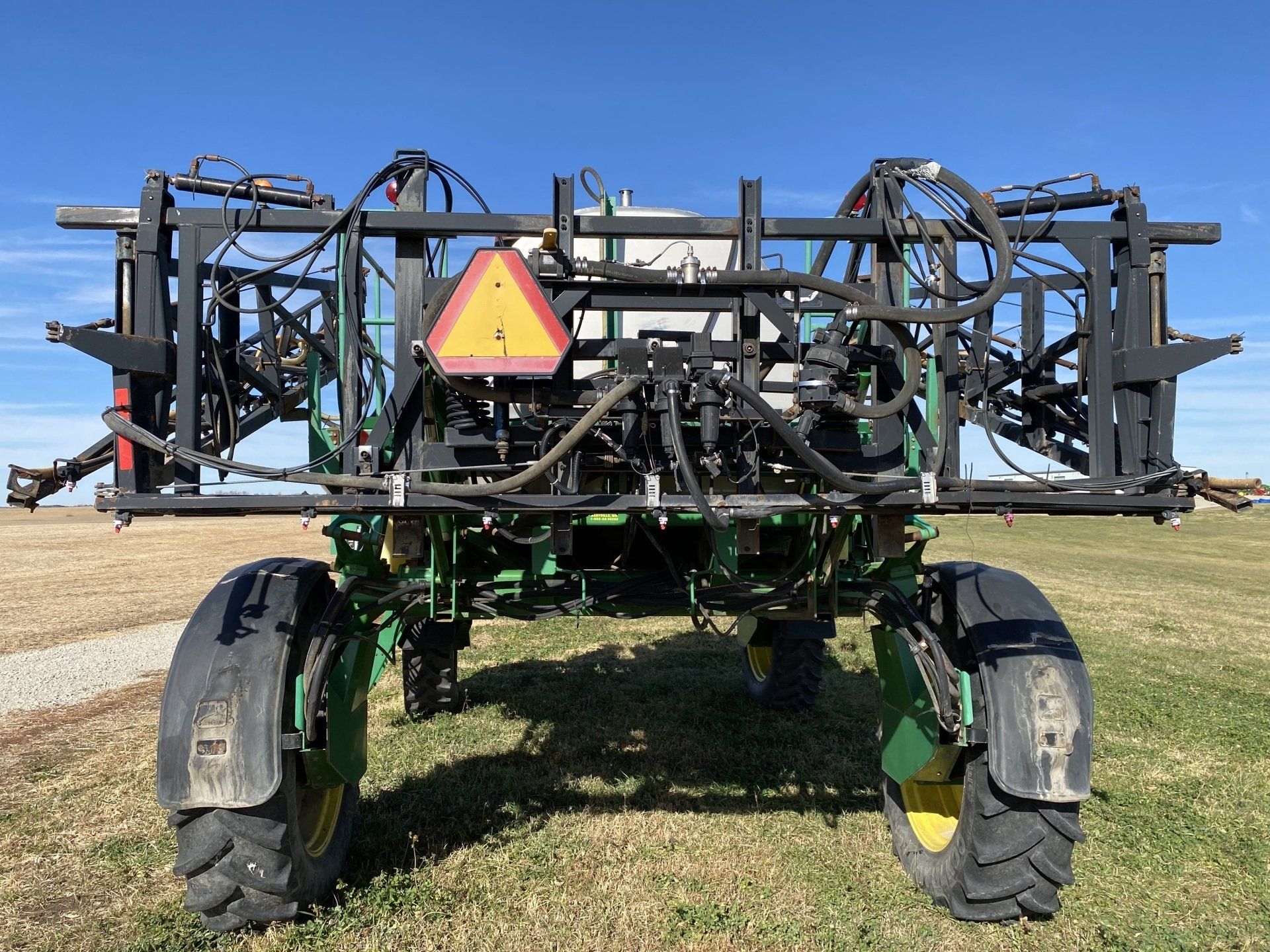 Green and black agricultural sprayer with large tires on a field.