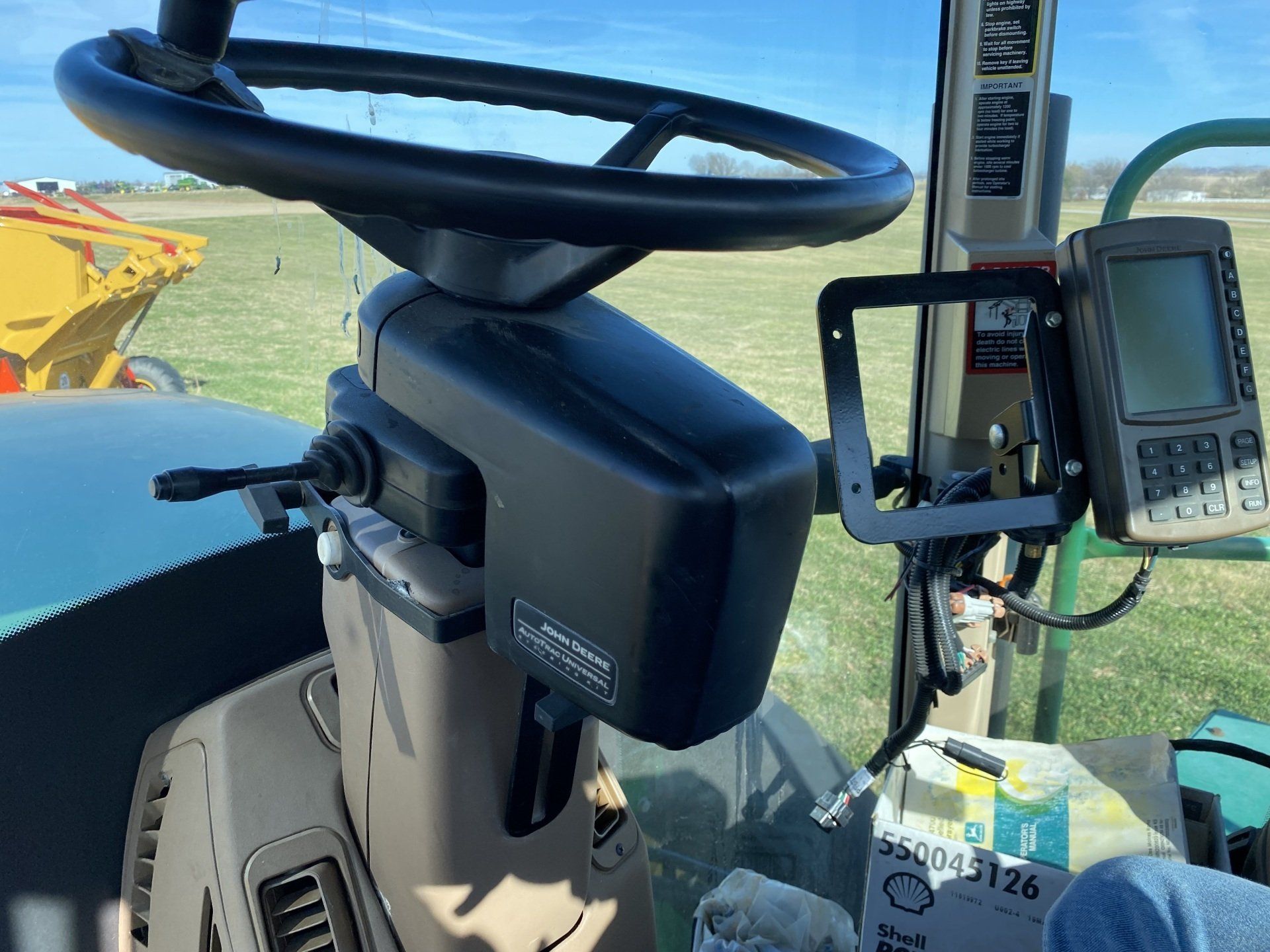 Interior of a tractor's cab with a steering wheel and a navigation screen mounted on the right.