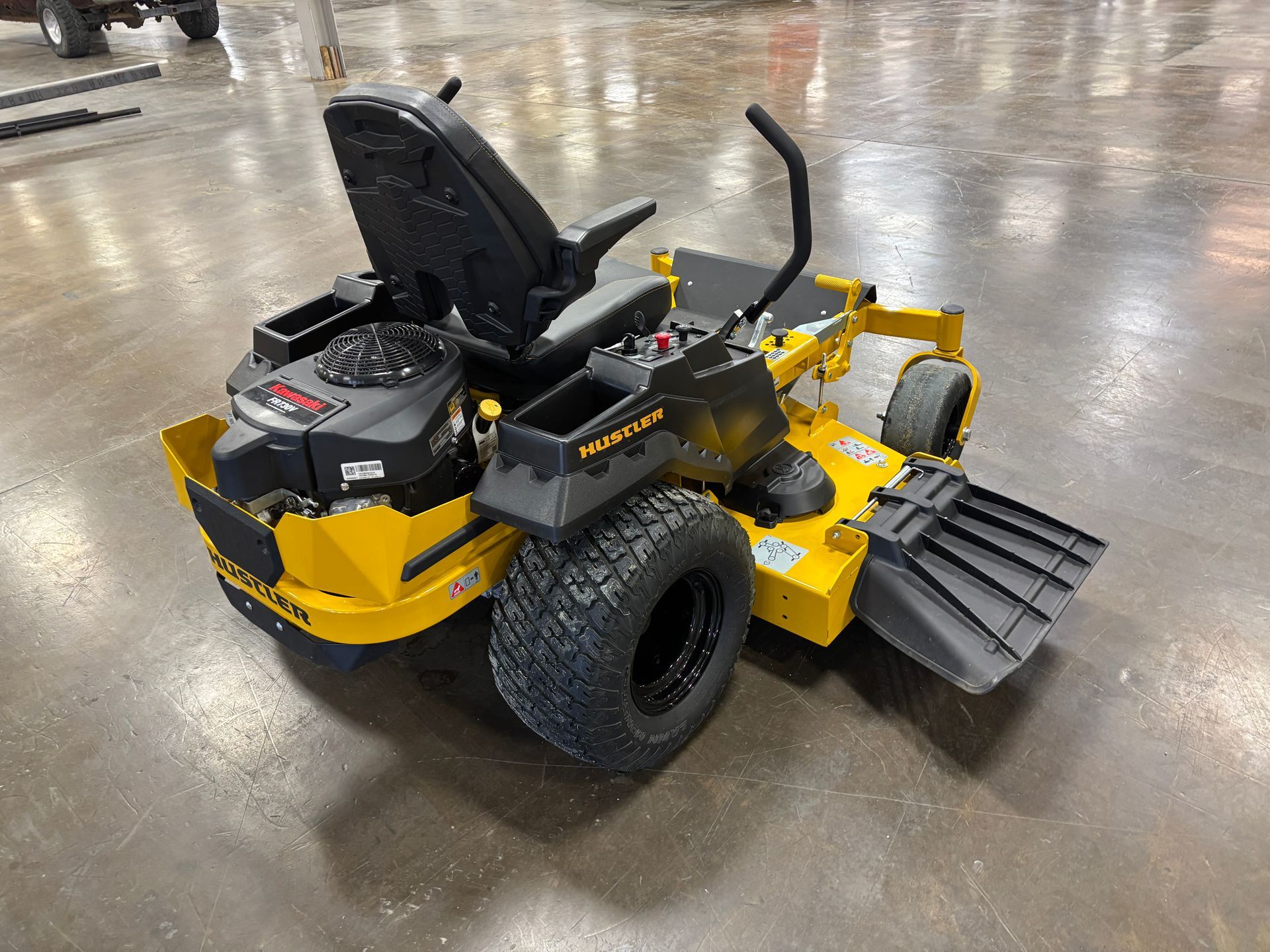 Yellow and black commercial zero-turn lawn mower with large tires on a concrete floor.