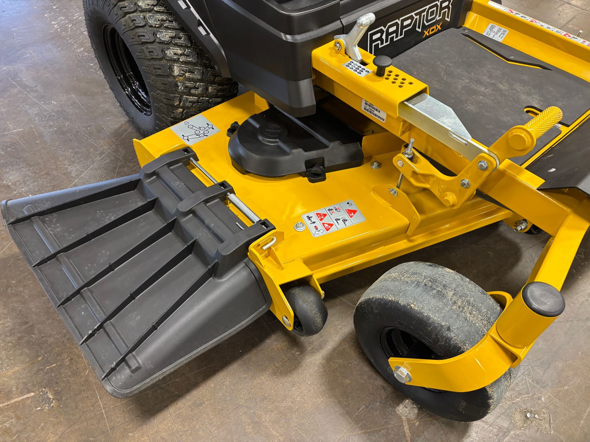 Yellow zero-turn mower with a black discharge chute, parked indoors.
