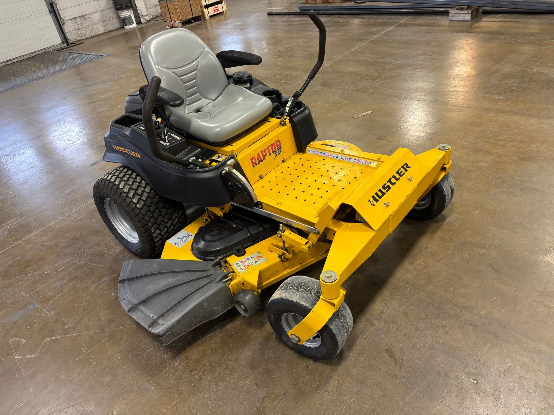 Yellow commercial zero-turn lawn mower on a concrete floor.