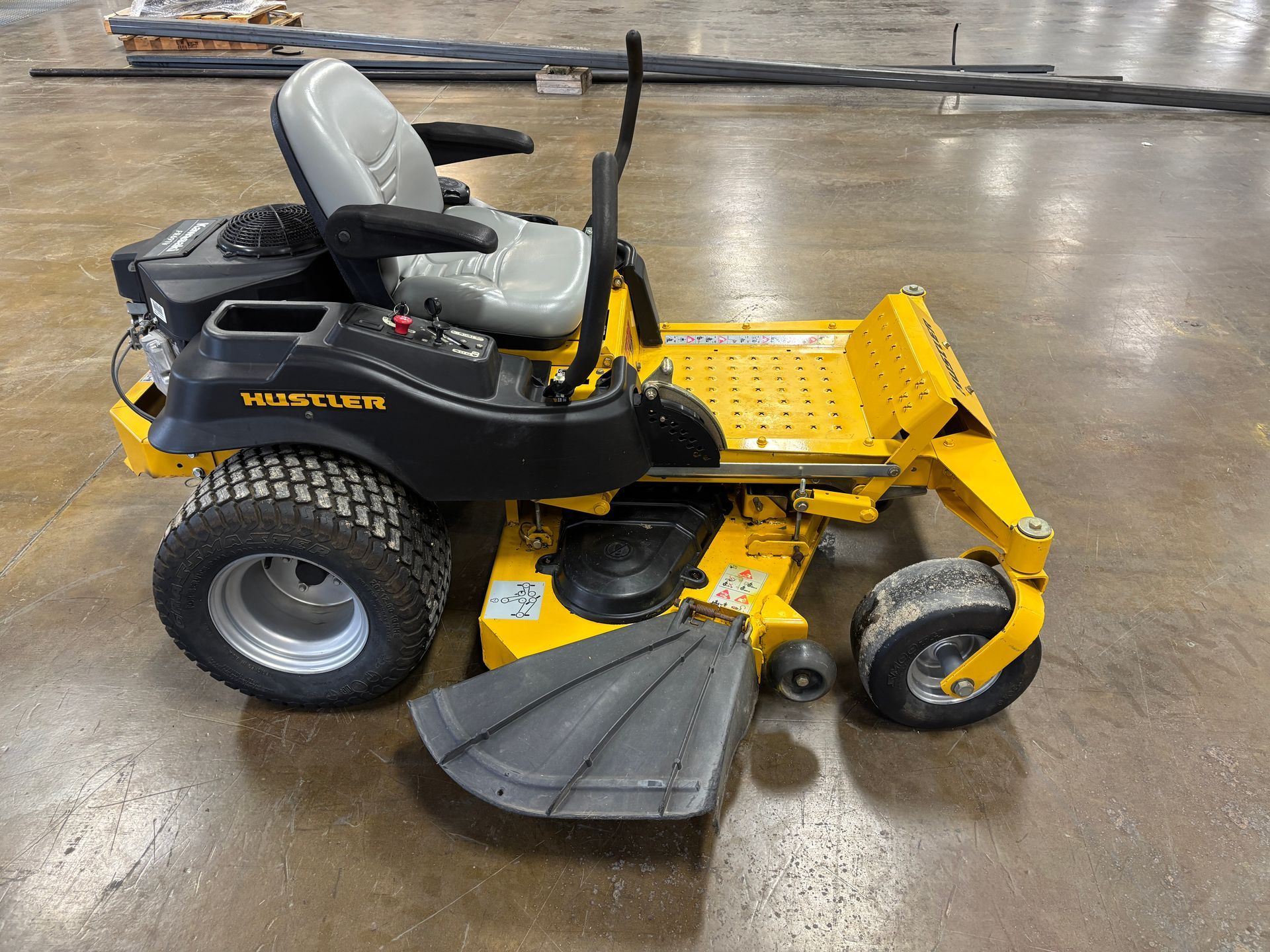 Yellow and black Hustler zero-turn lawnmower on a concrete surface.