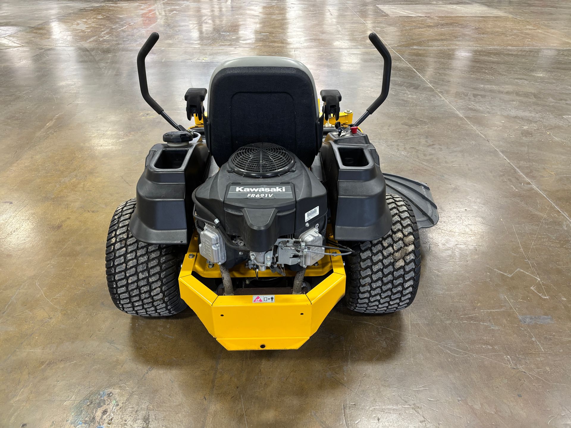 Yellow and black zero-turn lawn mower on a concrete surface.