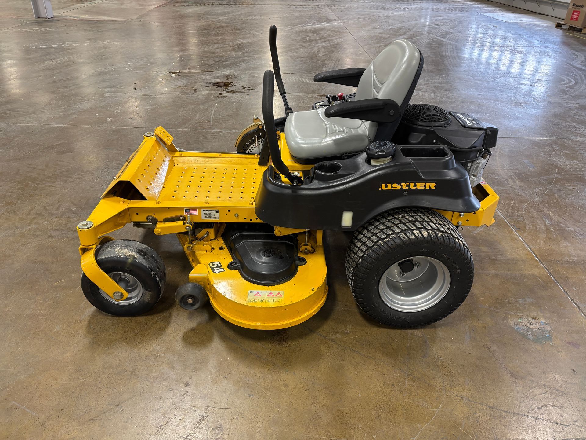 Yellow and black sit-down lawn mower on a concrete floor.