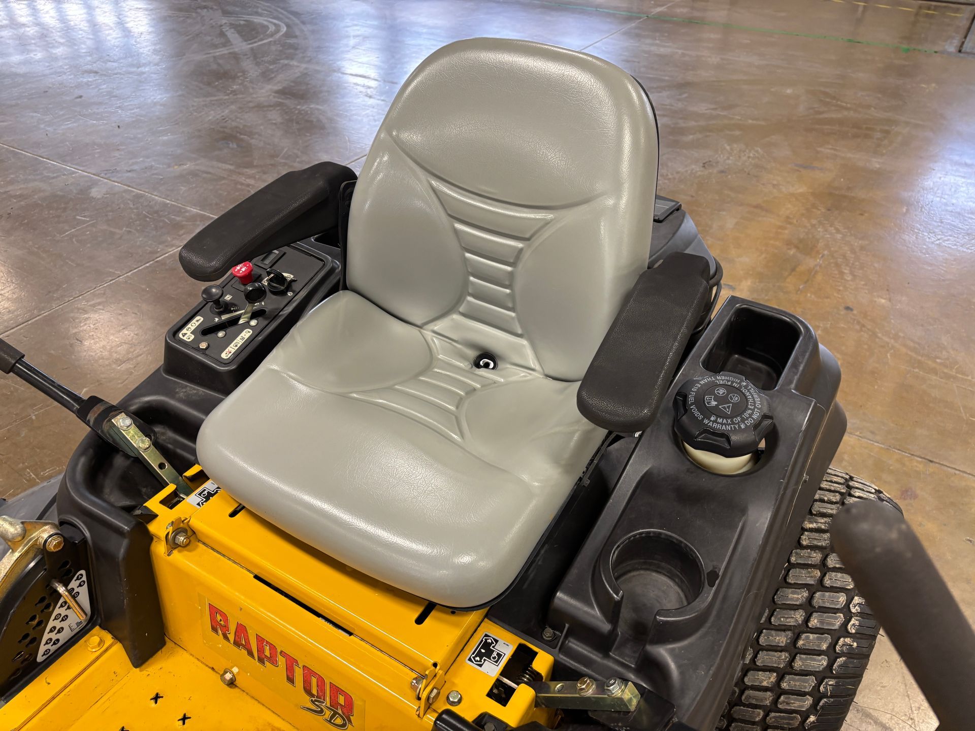 Yellow and black zero-turn lawnmower with a gray seat and armrests.