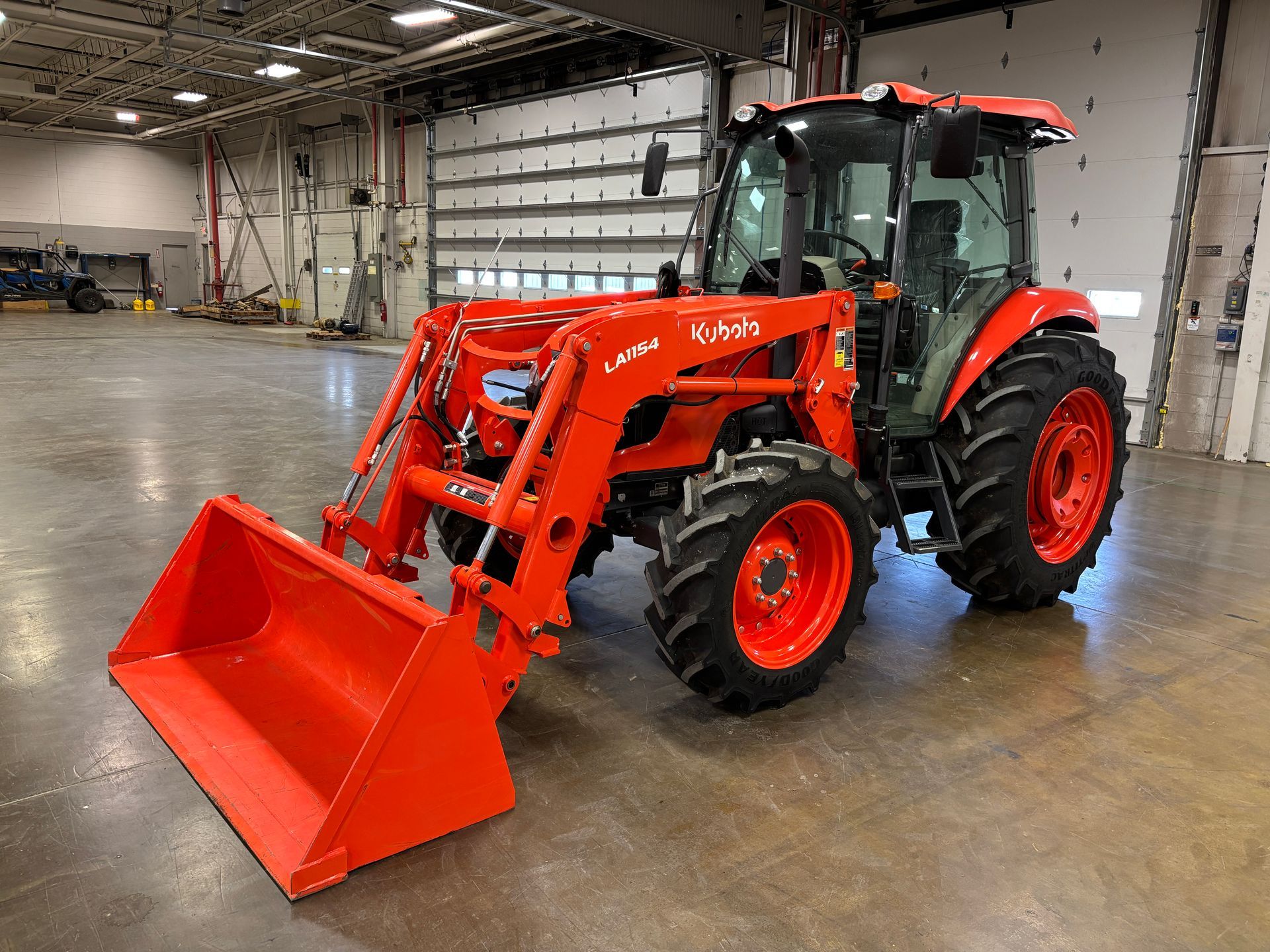 Orange tractor with front loader inside a building.