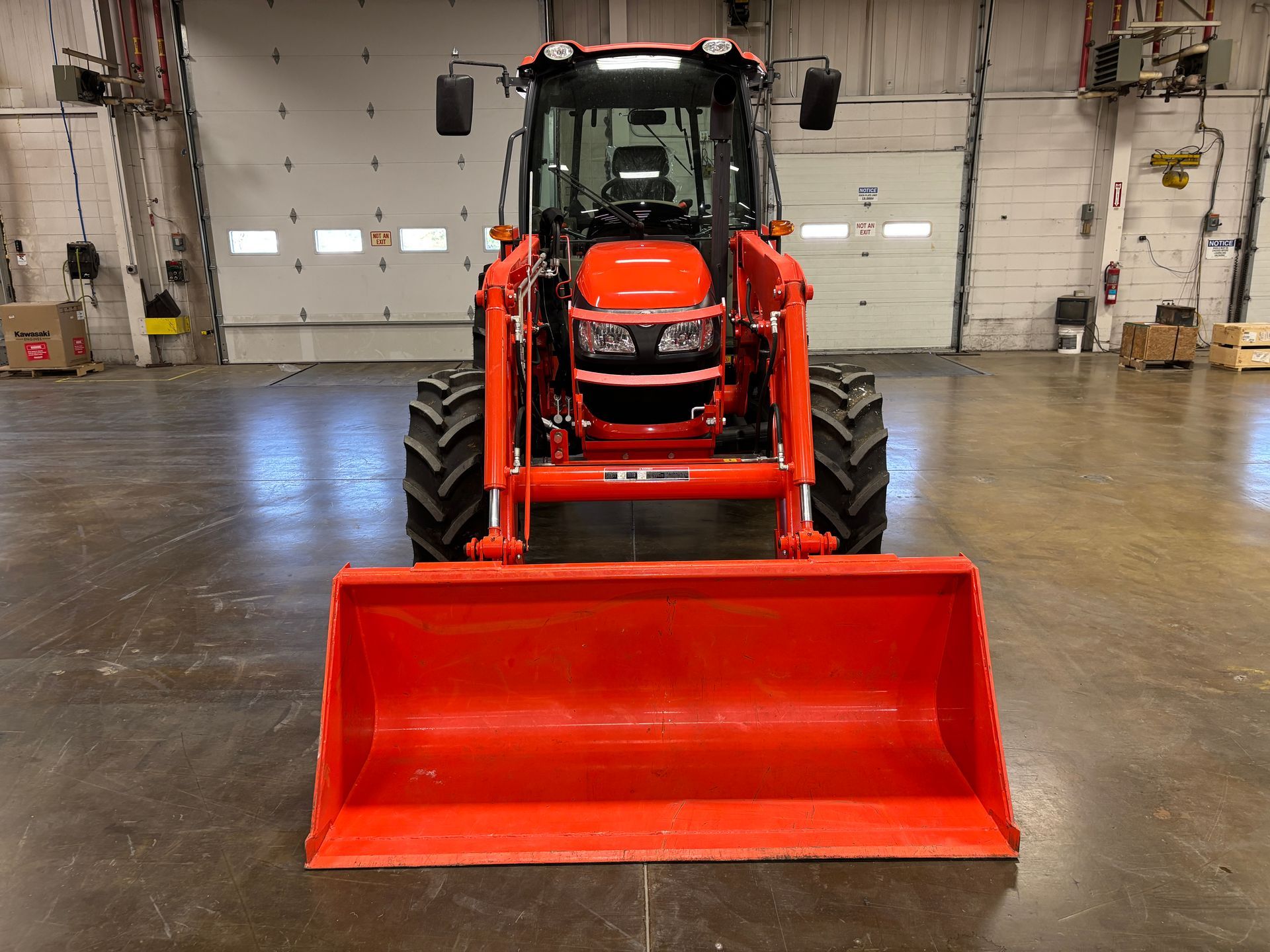 Orange tractor with front loader inside a building.