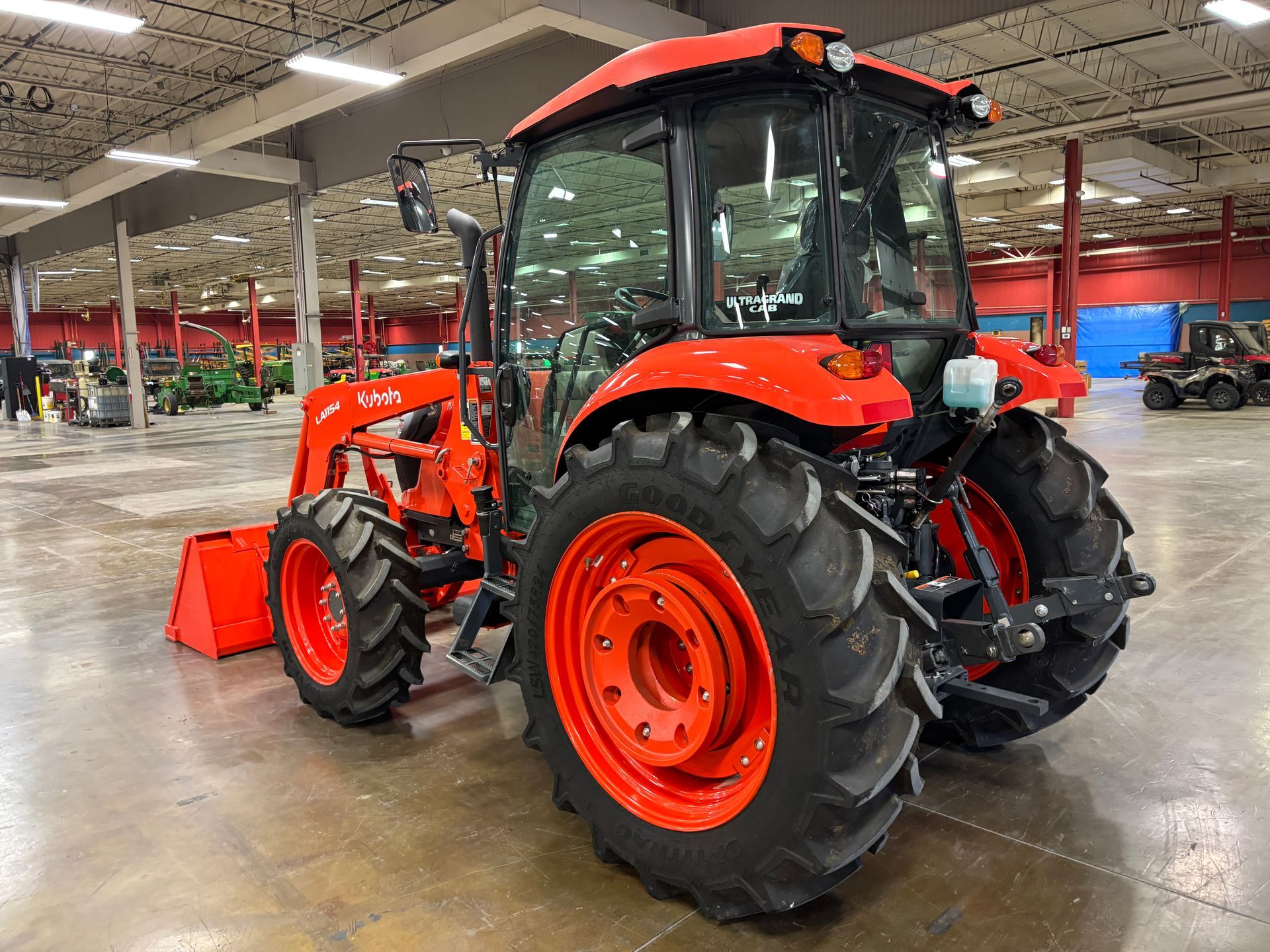 Orange Kubota tractor with front loader inside a large building.