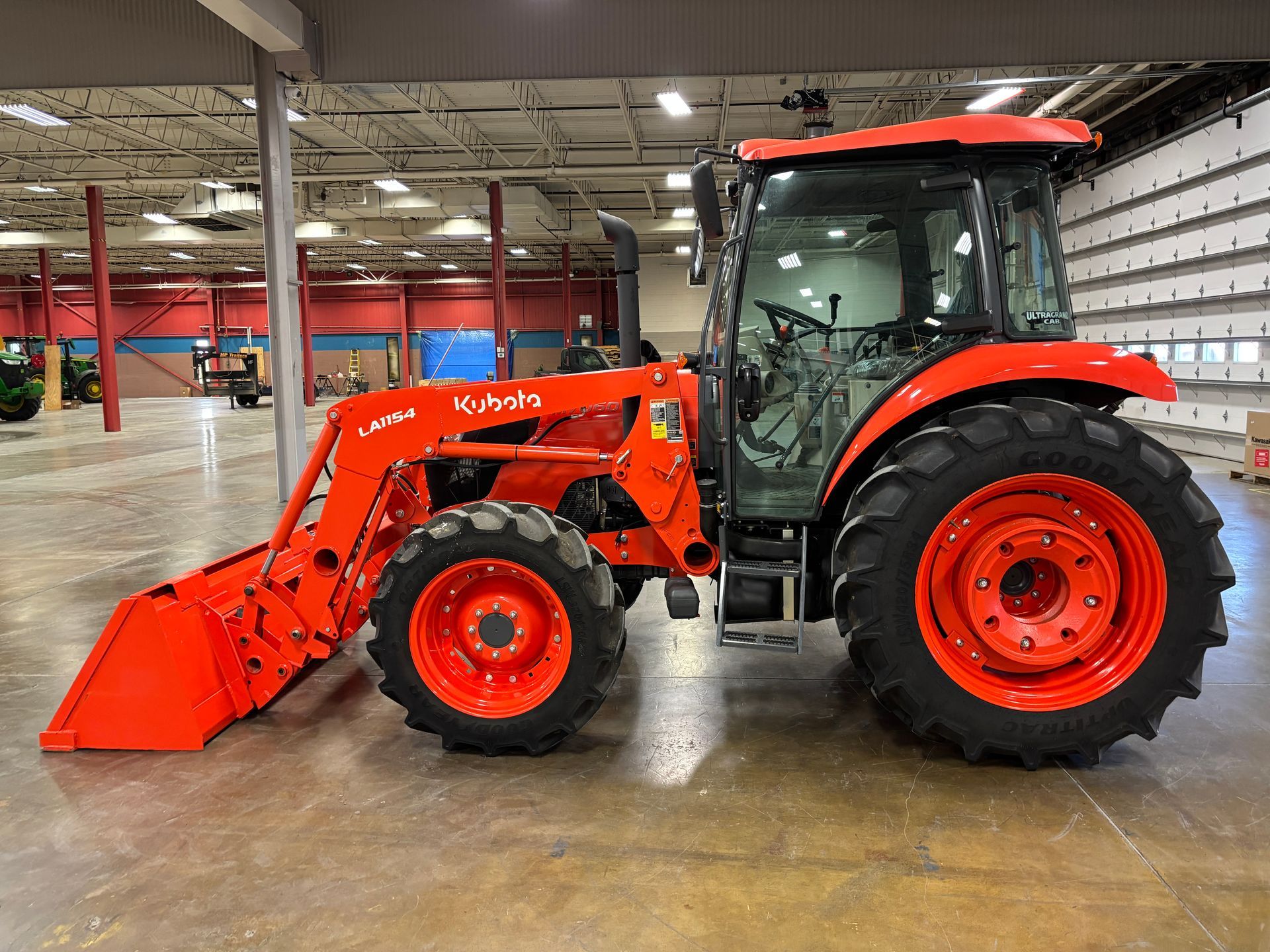Orange Kubota tractor with front loader inside a warehouse.