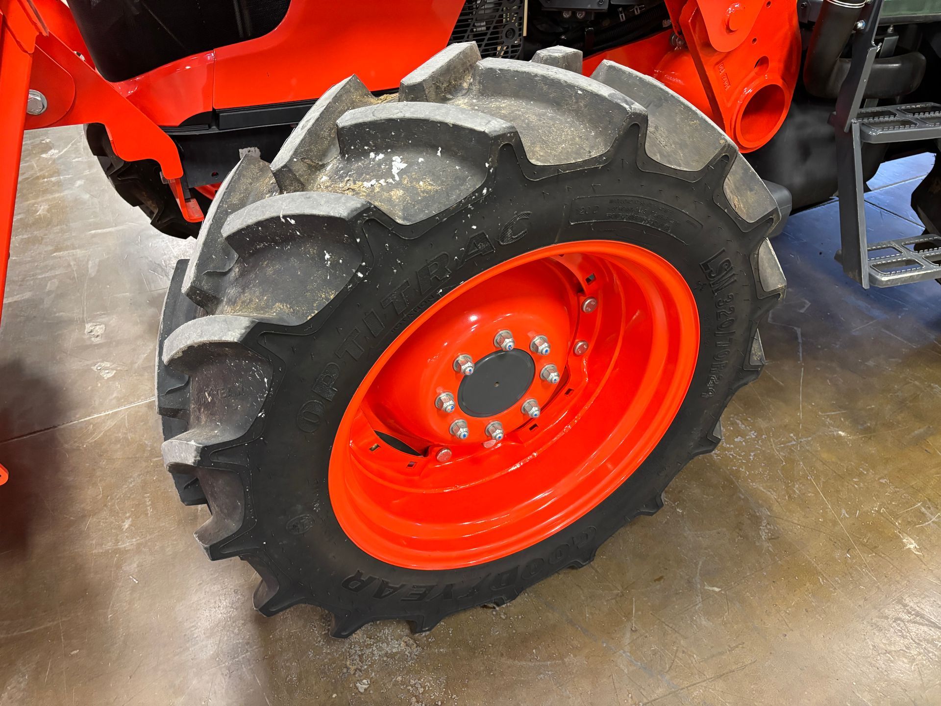 Orange tractor tire with black tread on a red wheel.