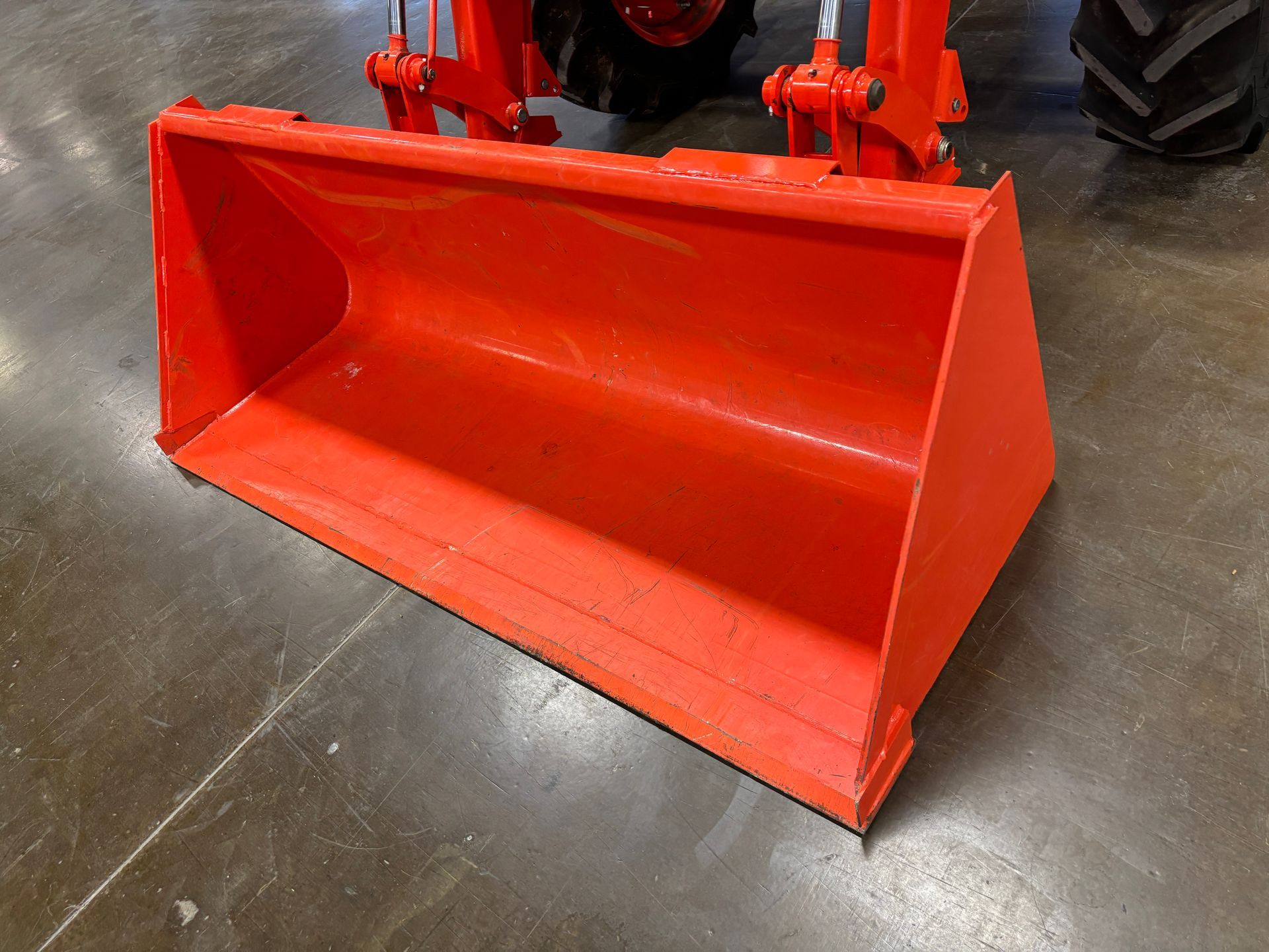 Orange tractor bucket on gray floor.