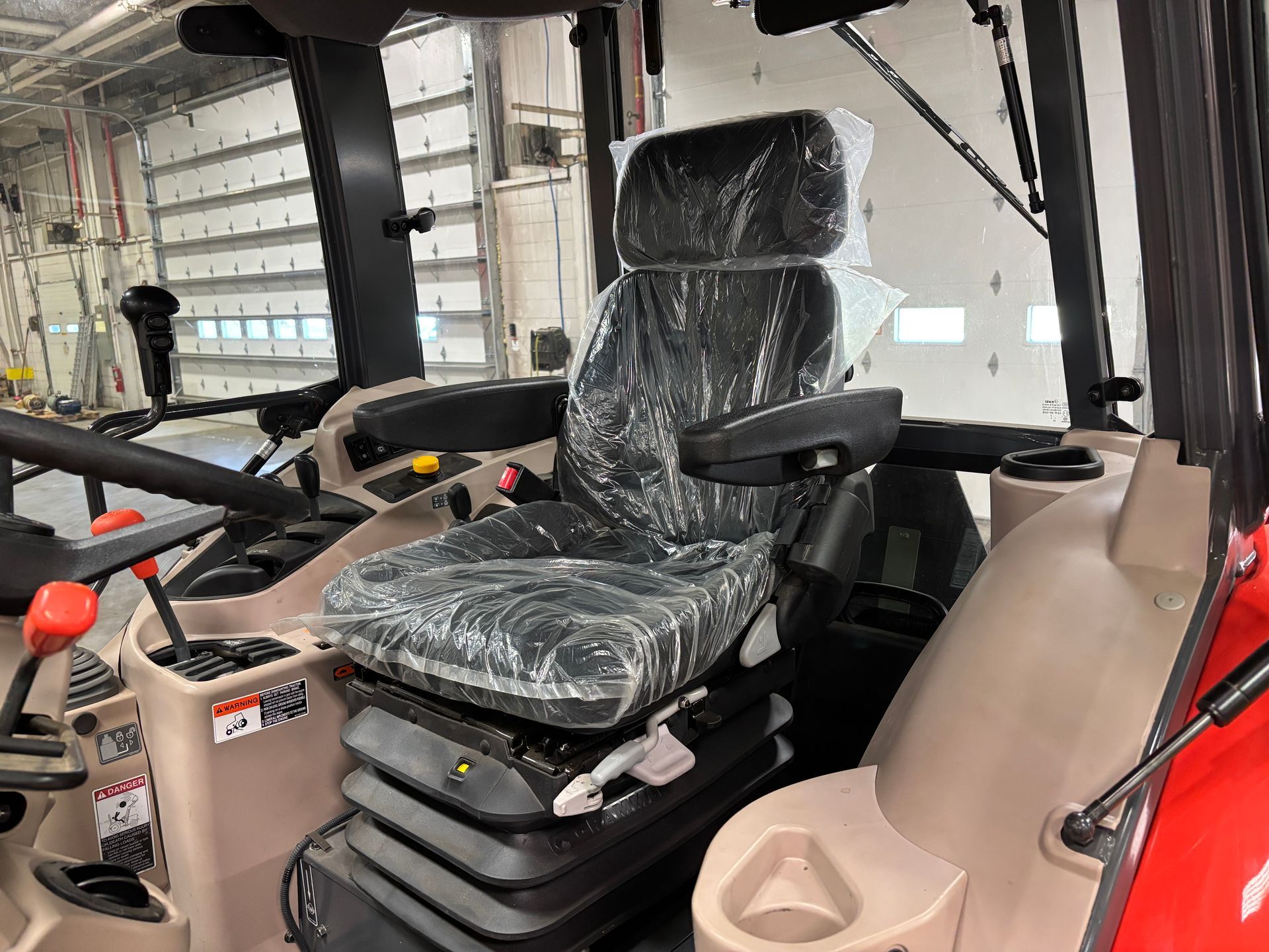 Interior of tractor cab with a seat covered in plastic.