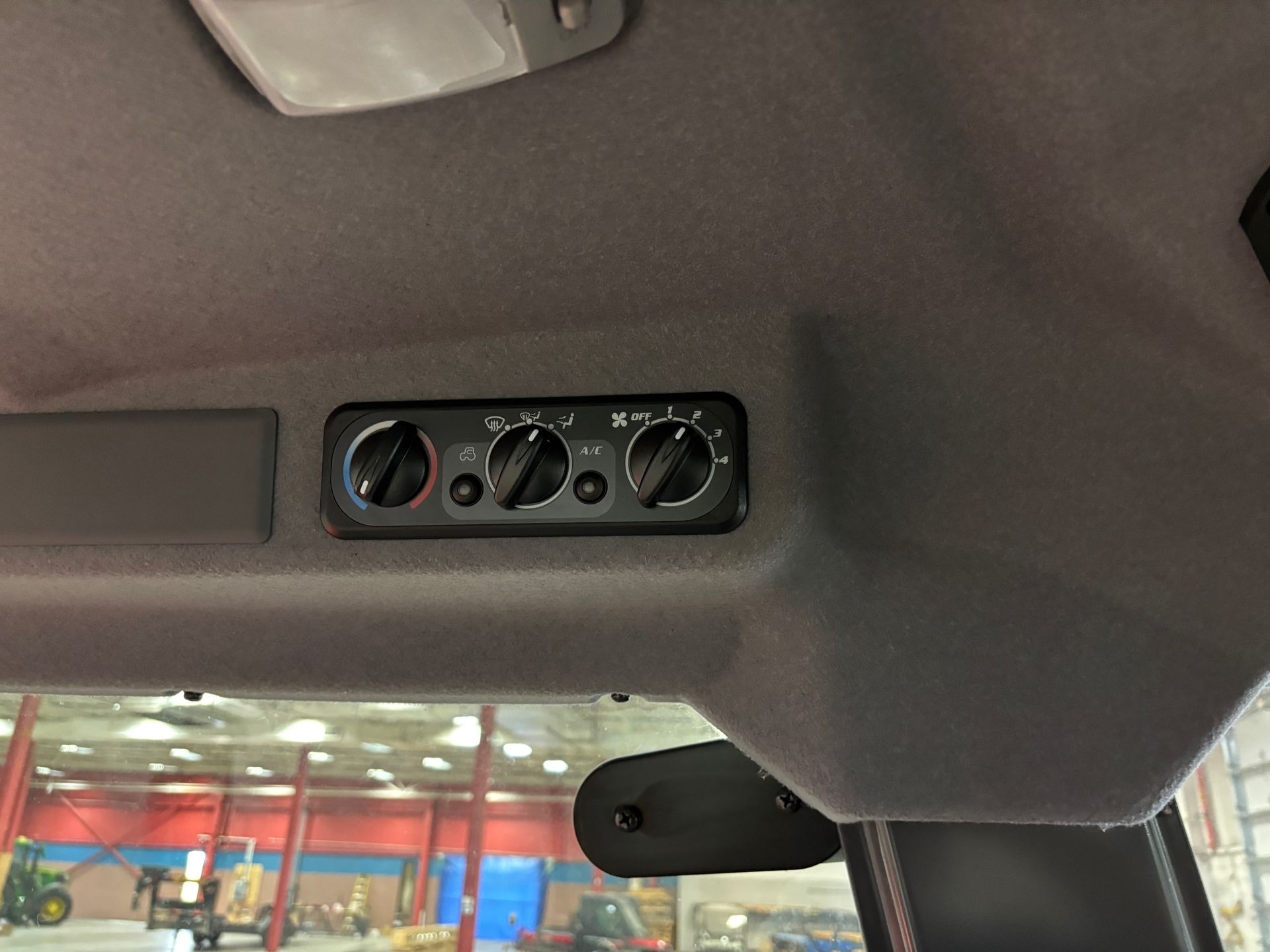 Control panel with three dials and buttons mounted on a vehicle's ceiling.