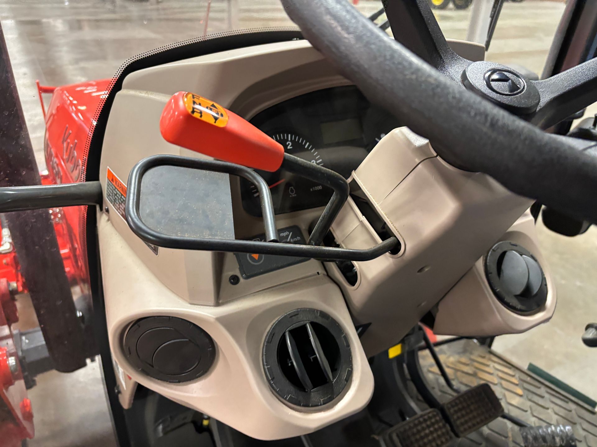 Interior of a tractor dashboard, including steering wheel, levers, gauges, and air vents, in beige and black.