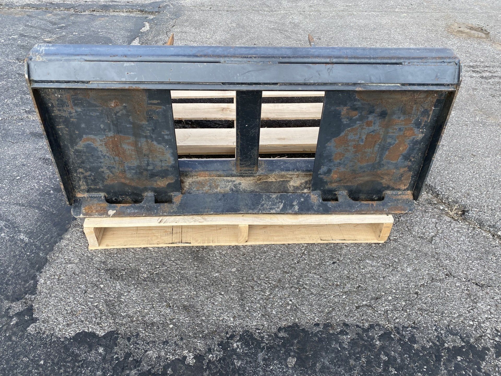 Bale spear attachment sitting on a wooden pallet.