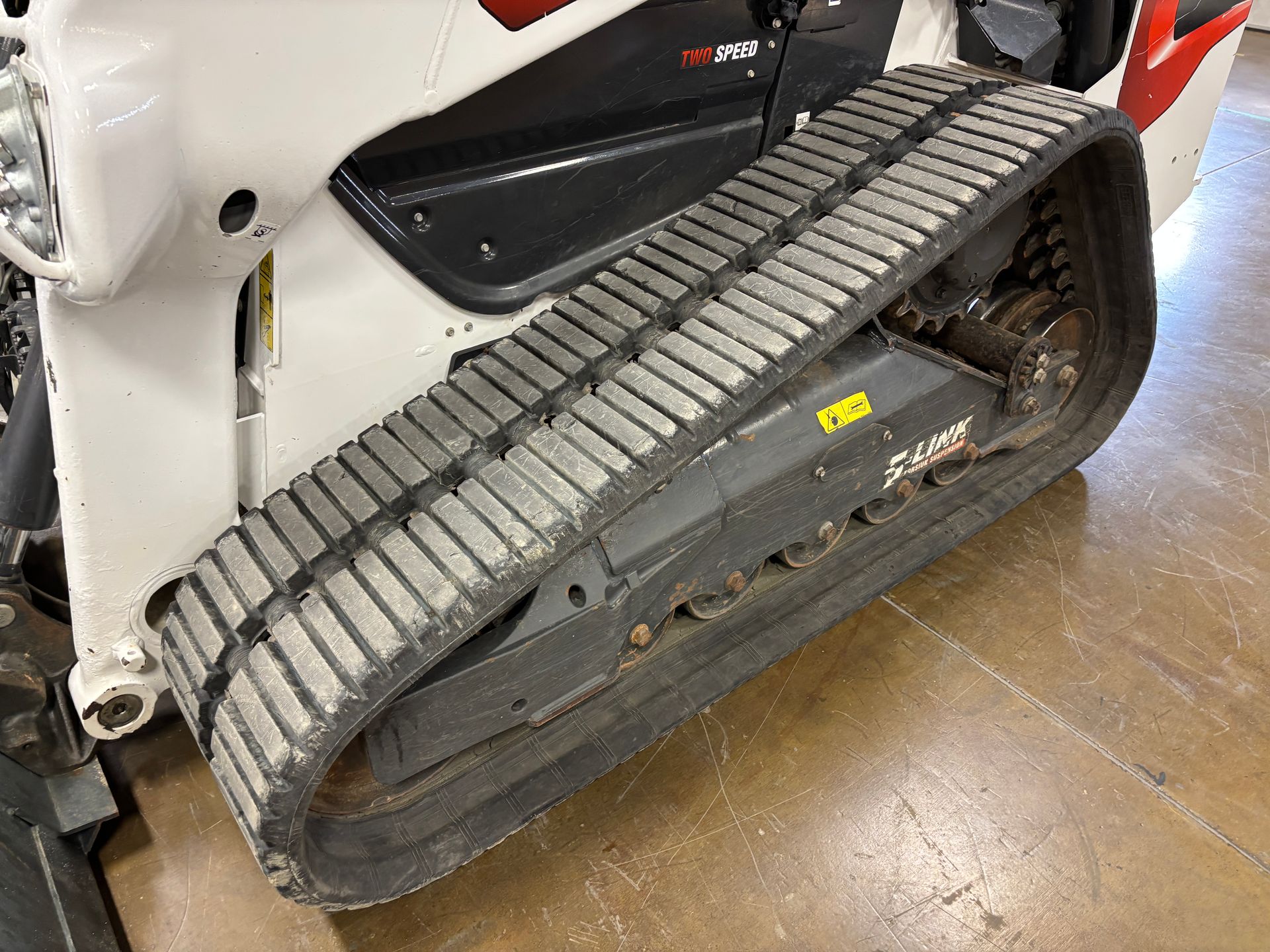 White Bobcat compact track loader, close up of black tracks.