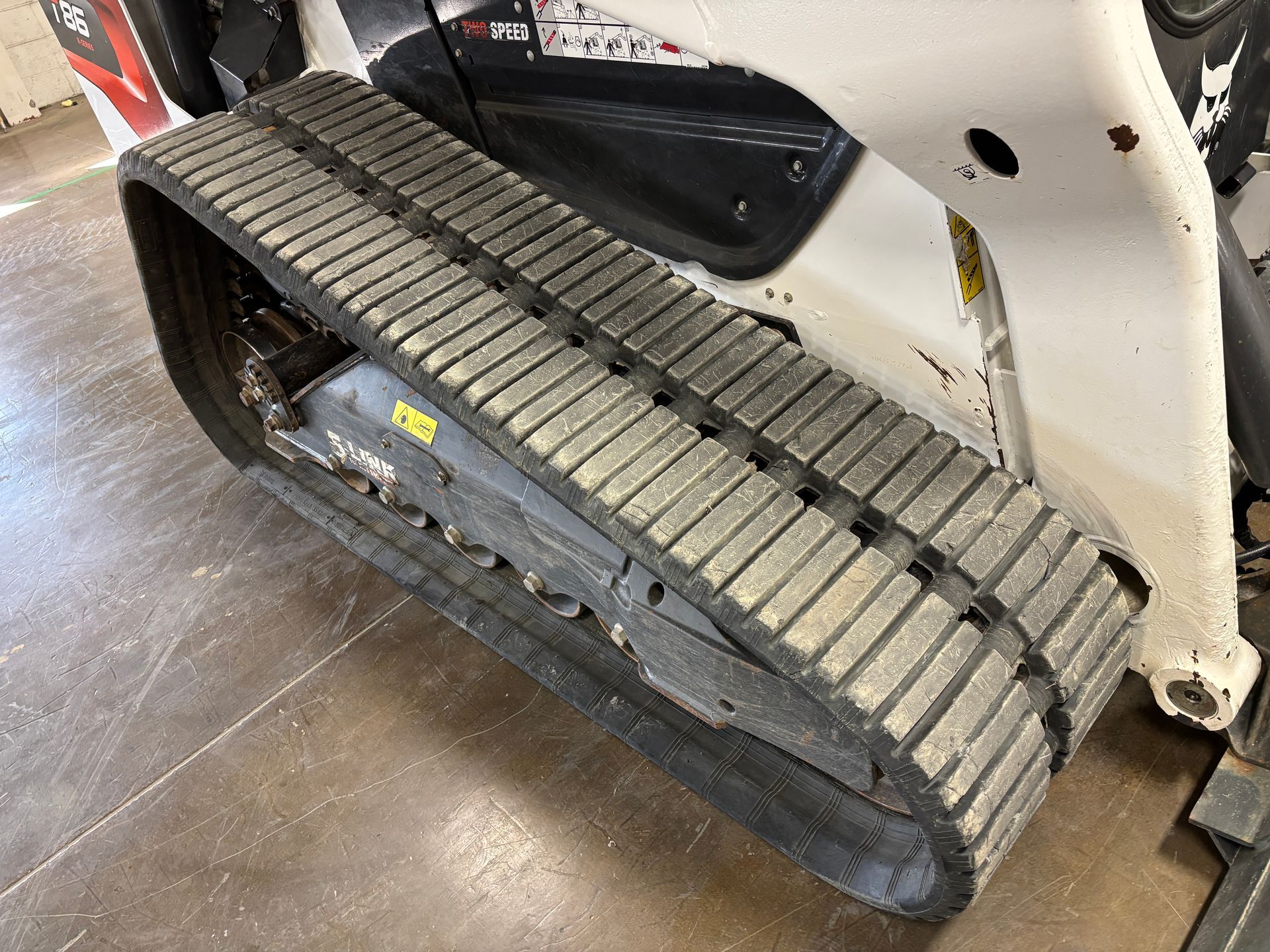 White Bobcat compact track loader, close up of black tracks.