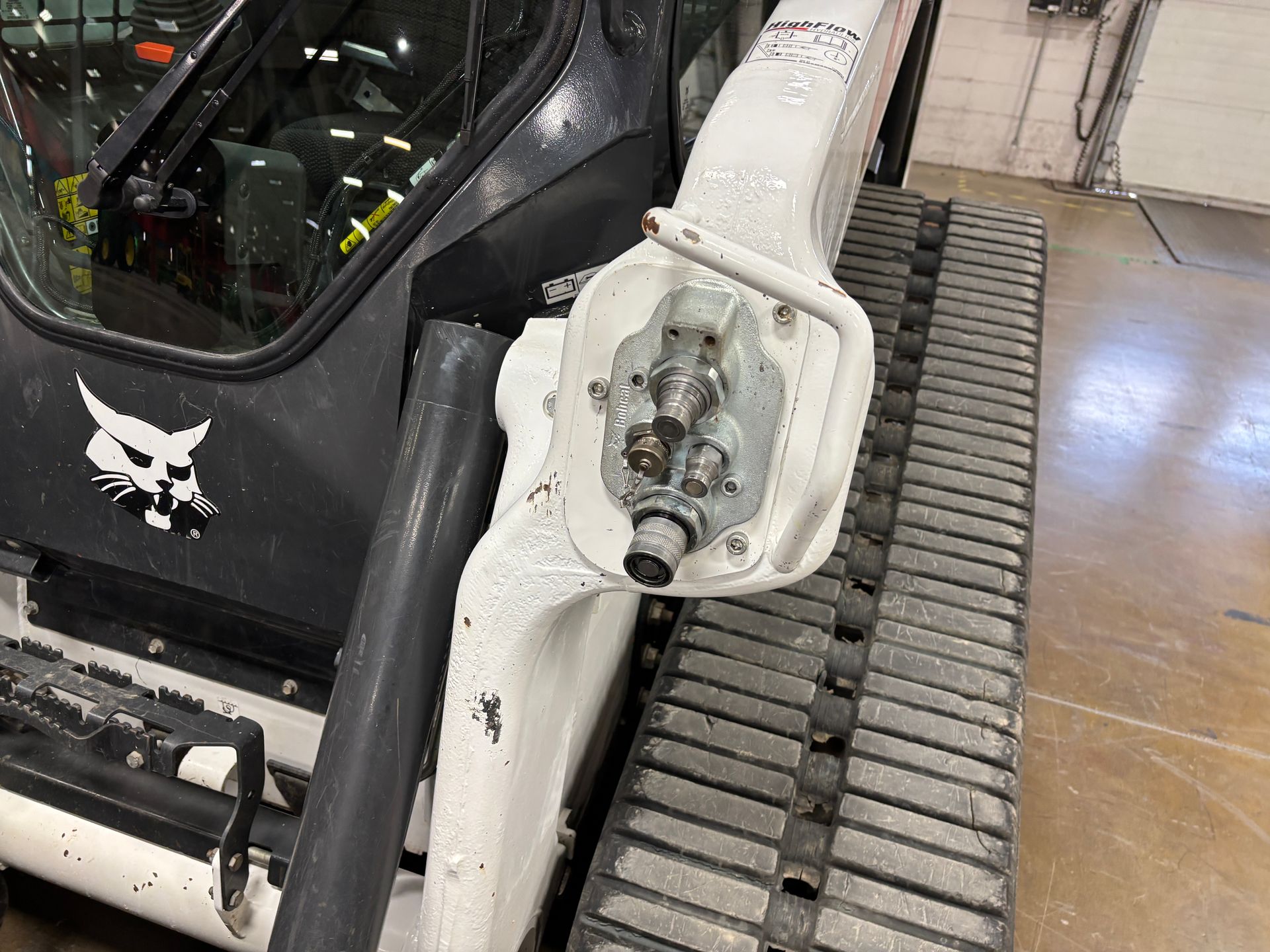 Bobcat compact track loader attachment arm, with hydraulic connectors, near track.