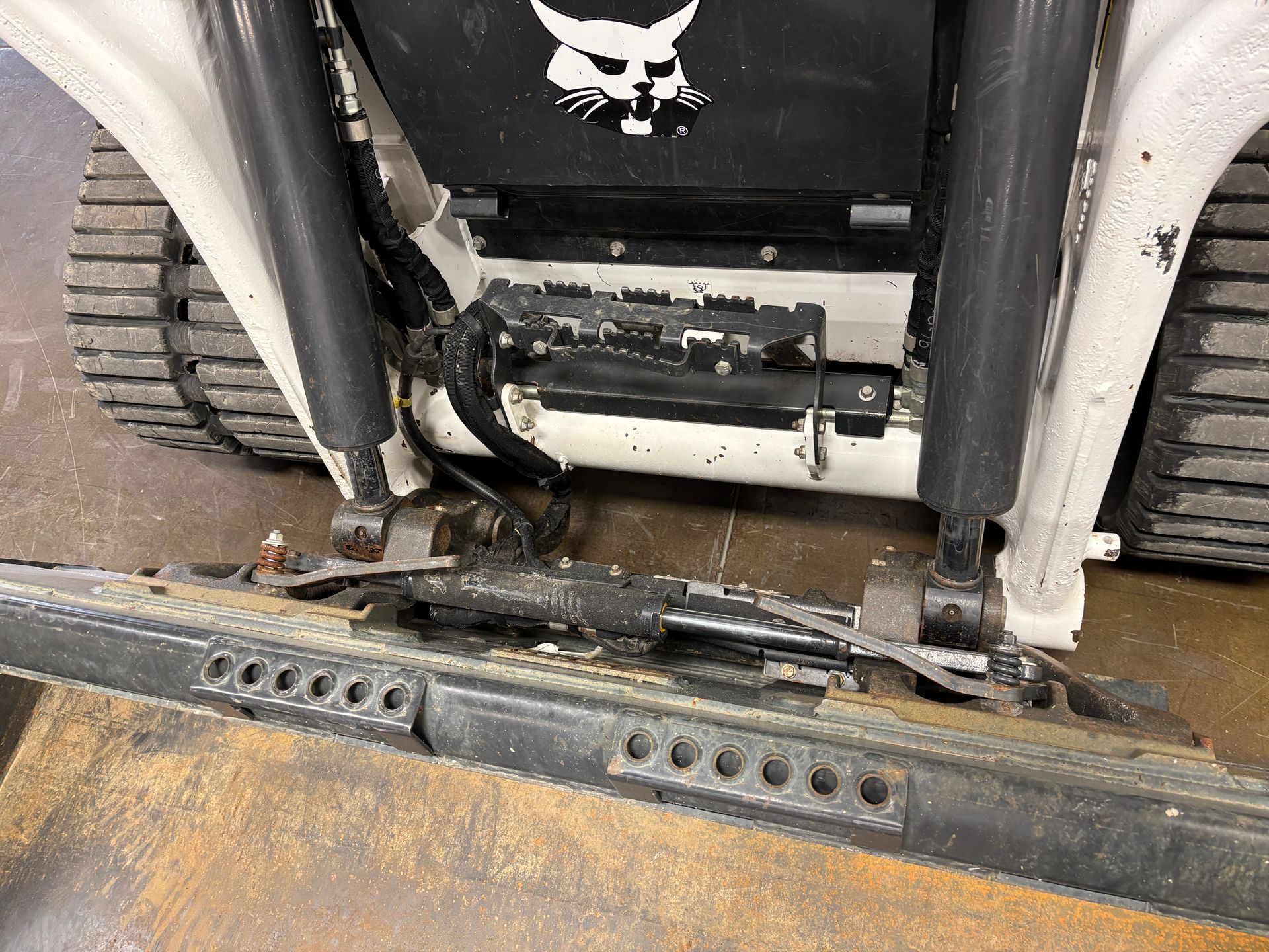 Bobcat compact track loader's front with black tracks, showing near the bucket.