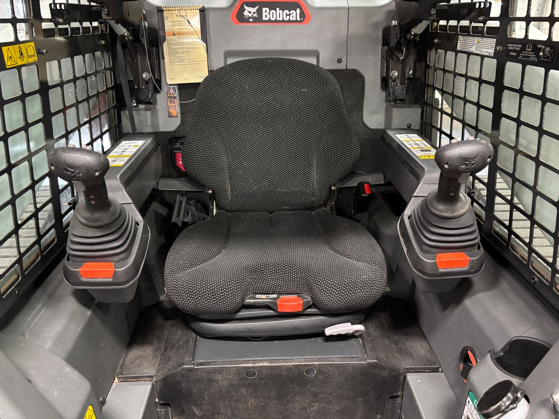 Interior of a Bobcat compact track loader, showing seat and control levers.