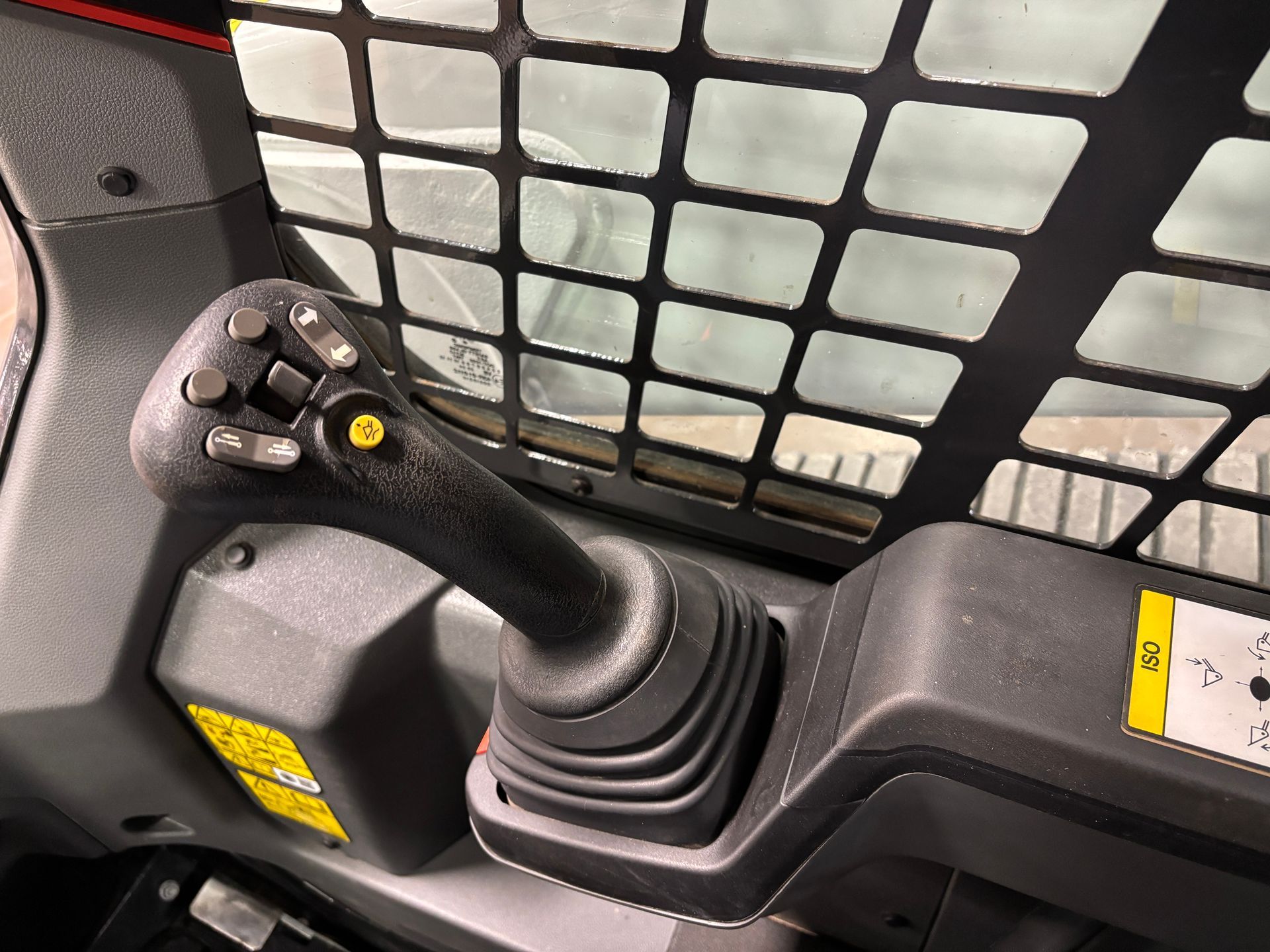 Black joystick control in a compact track loader cabin.