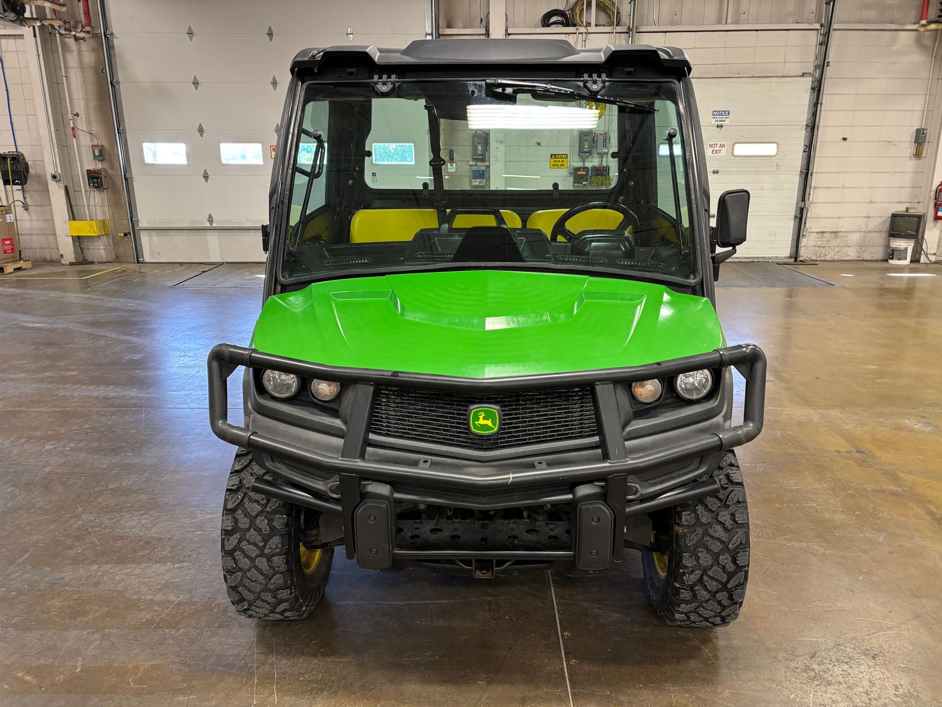 Green and black John Deere Gator utility vehicle with a front grill and headlights.