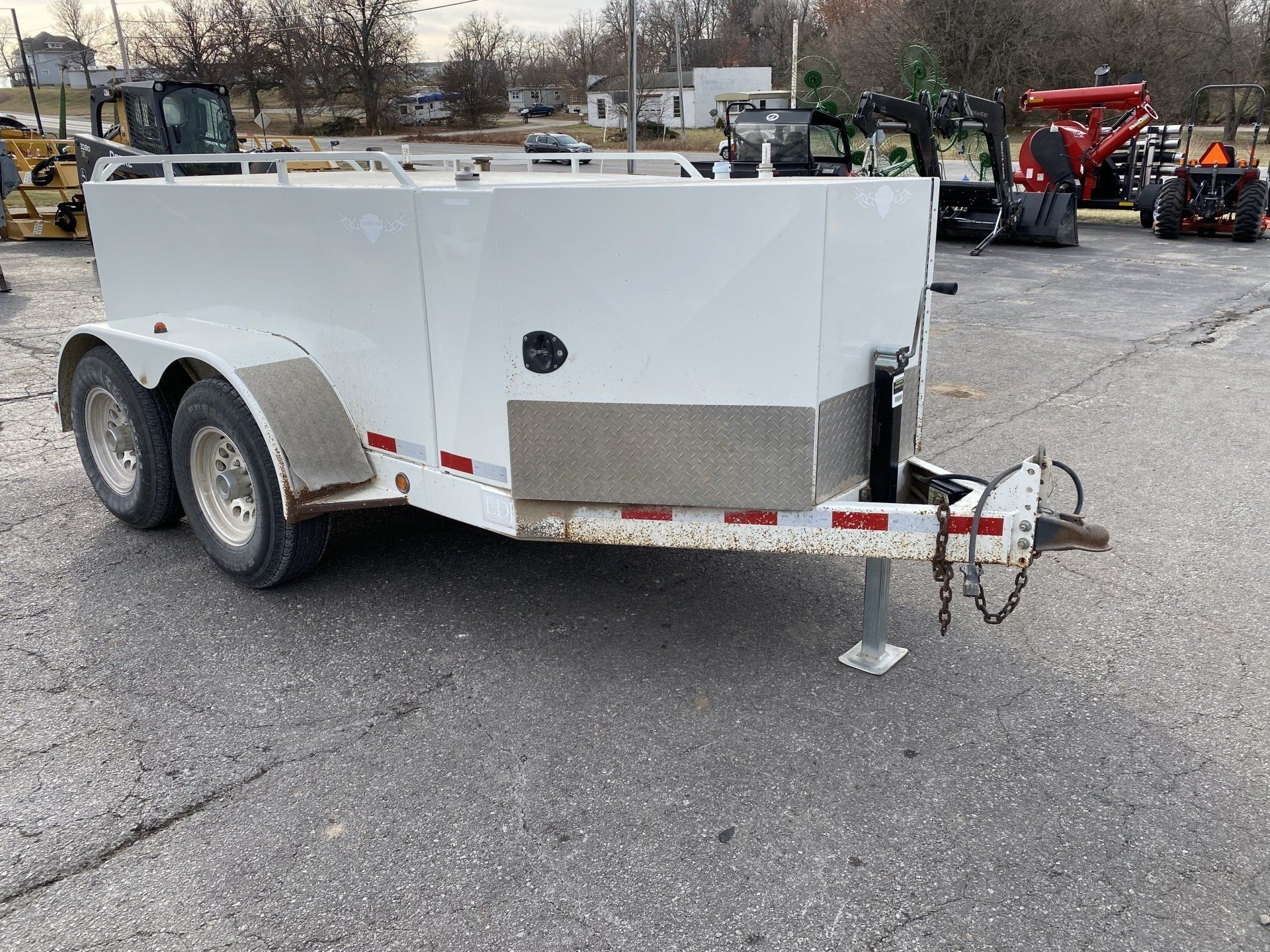 White fuel trailer with a silver front panel, parked on asphalt, front angled shot.