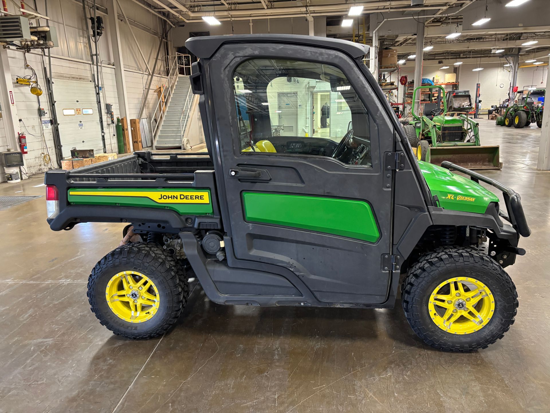 John Deere utility vehicle with black and green body and yellow wheels.