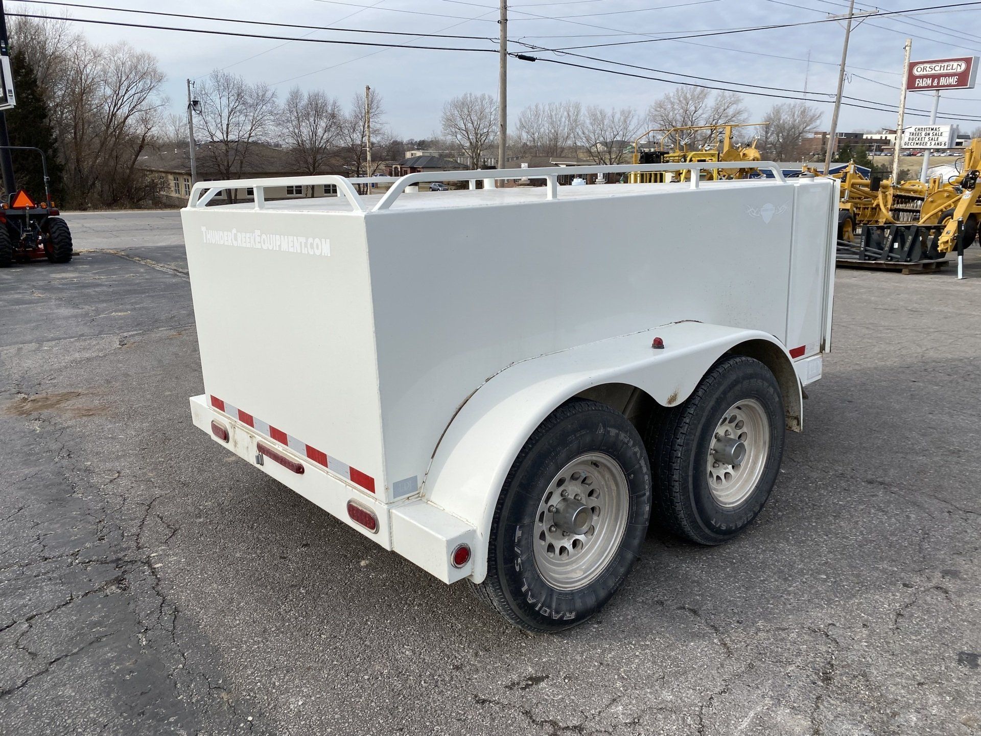 White fuel trailer with a silver front panel, parked on asphalt, back angled shot.