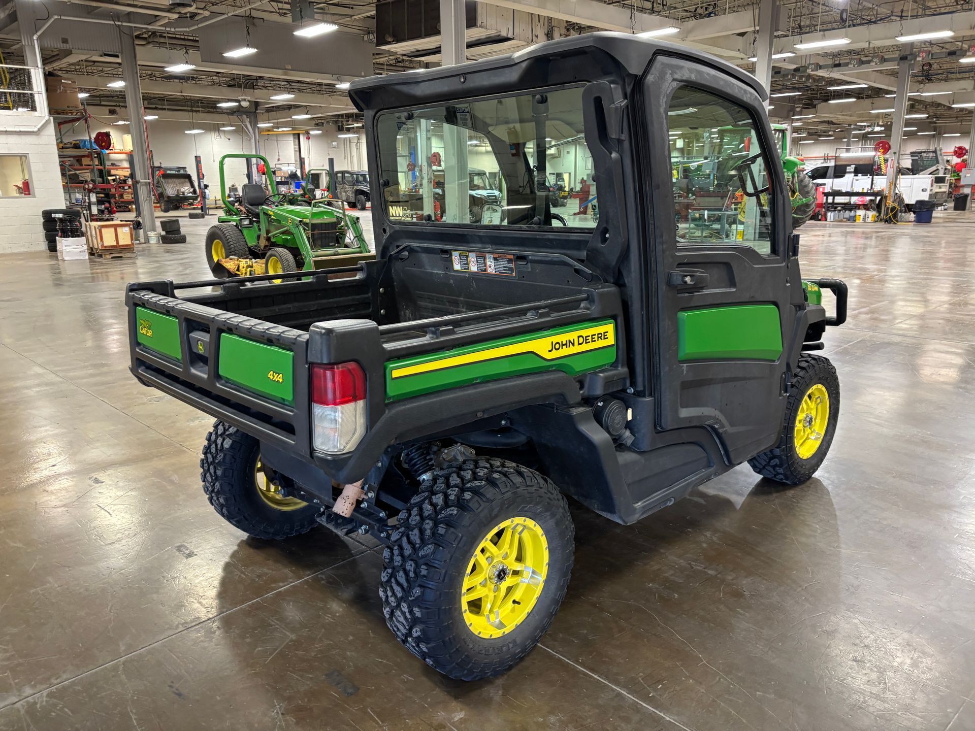 John Deere Gator utility vehicle, black and green, in a large warehouse.