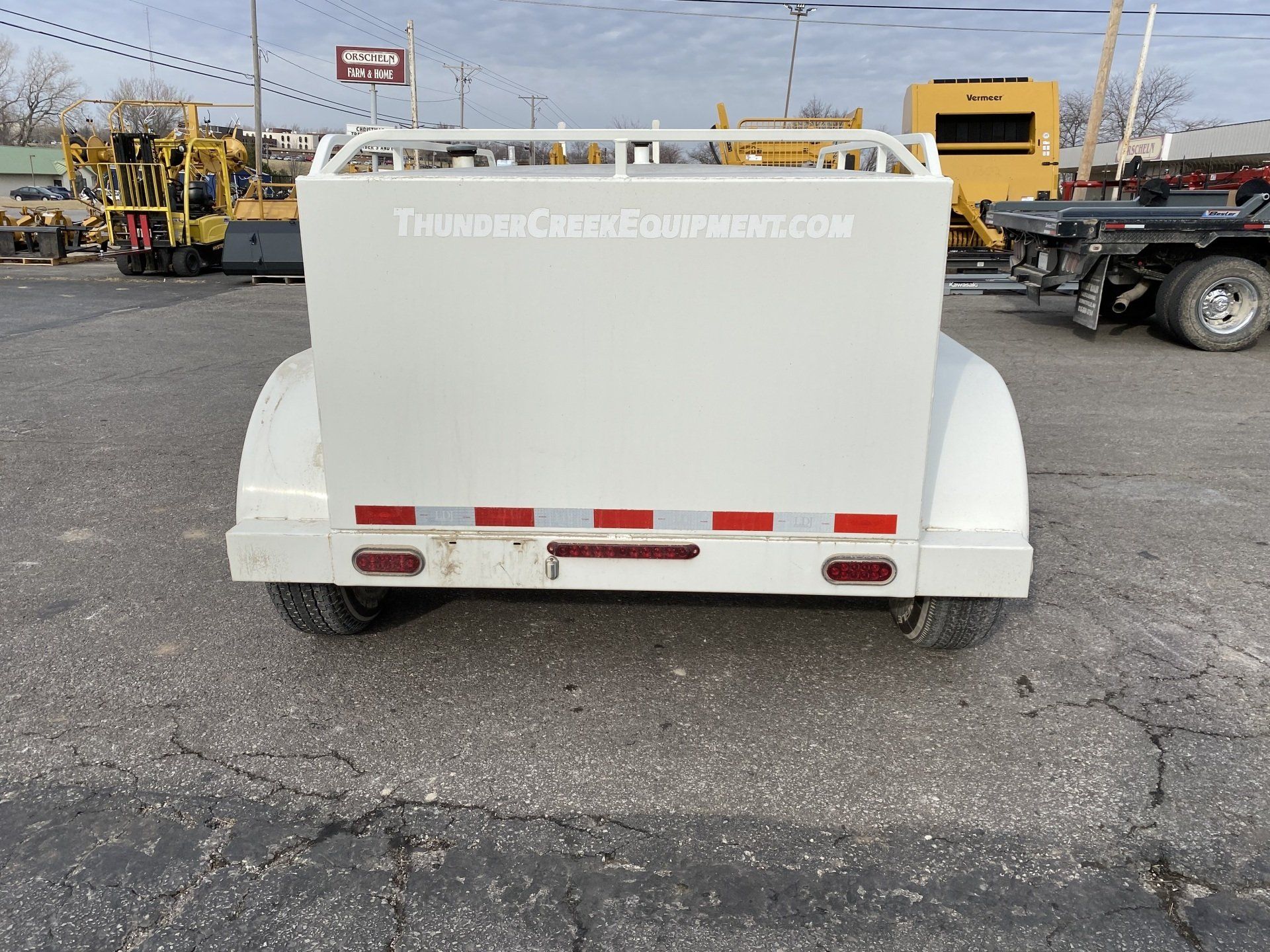 White fuel trailer with a silver front panel, parked on asphalt, back shot.