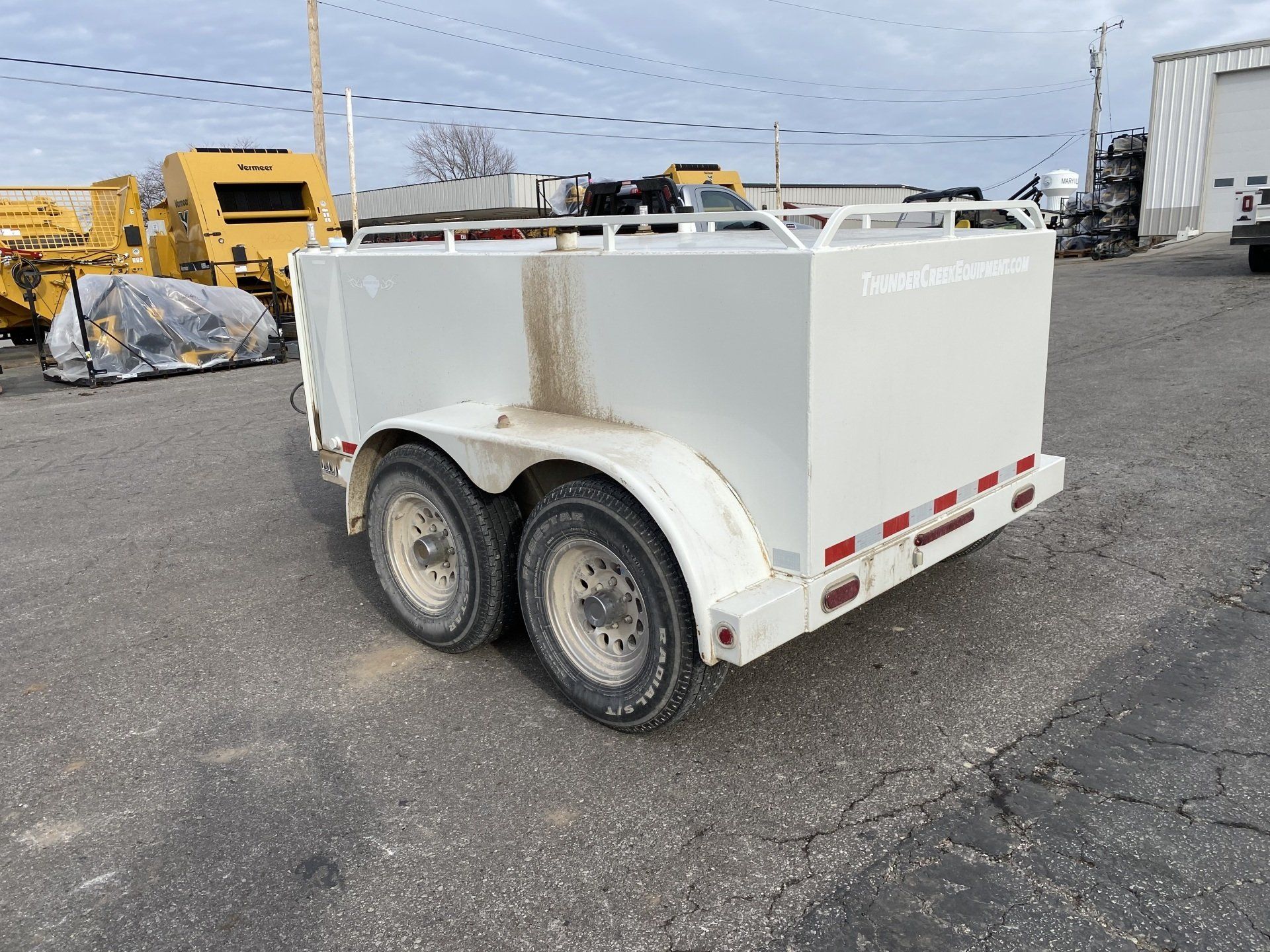 White fuel trailer with a silver front panel, parked on asphalt, back angled shot.