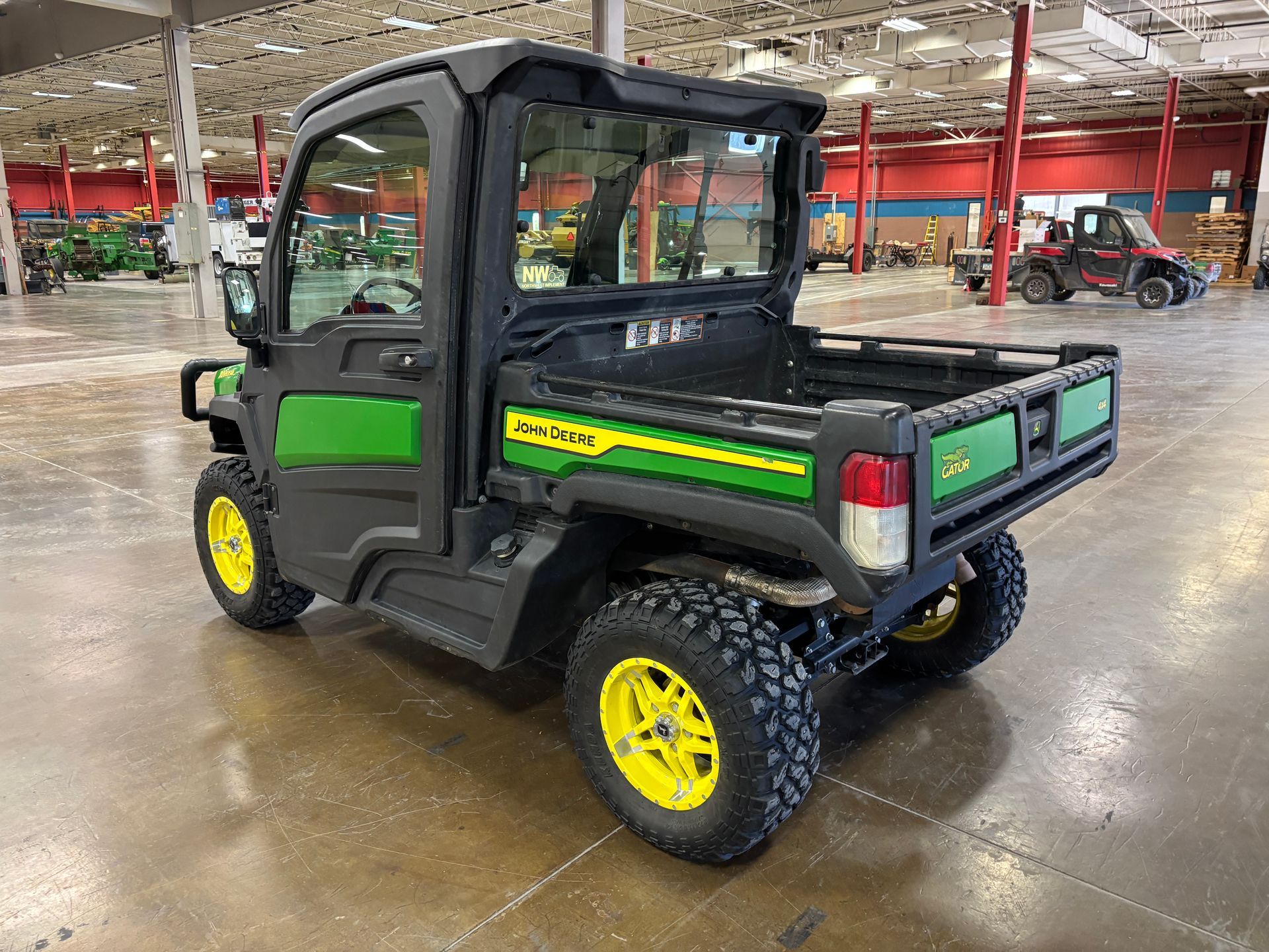 John Deere Gator utility vehicle with a black cab and green and yellow accents.